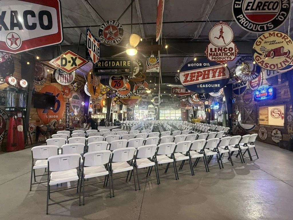 Indoor hall at Sparks Museum and Event Center with rows of white chairs under vintage signs