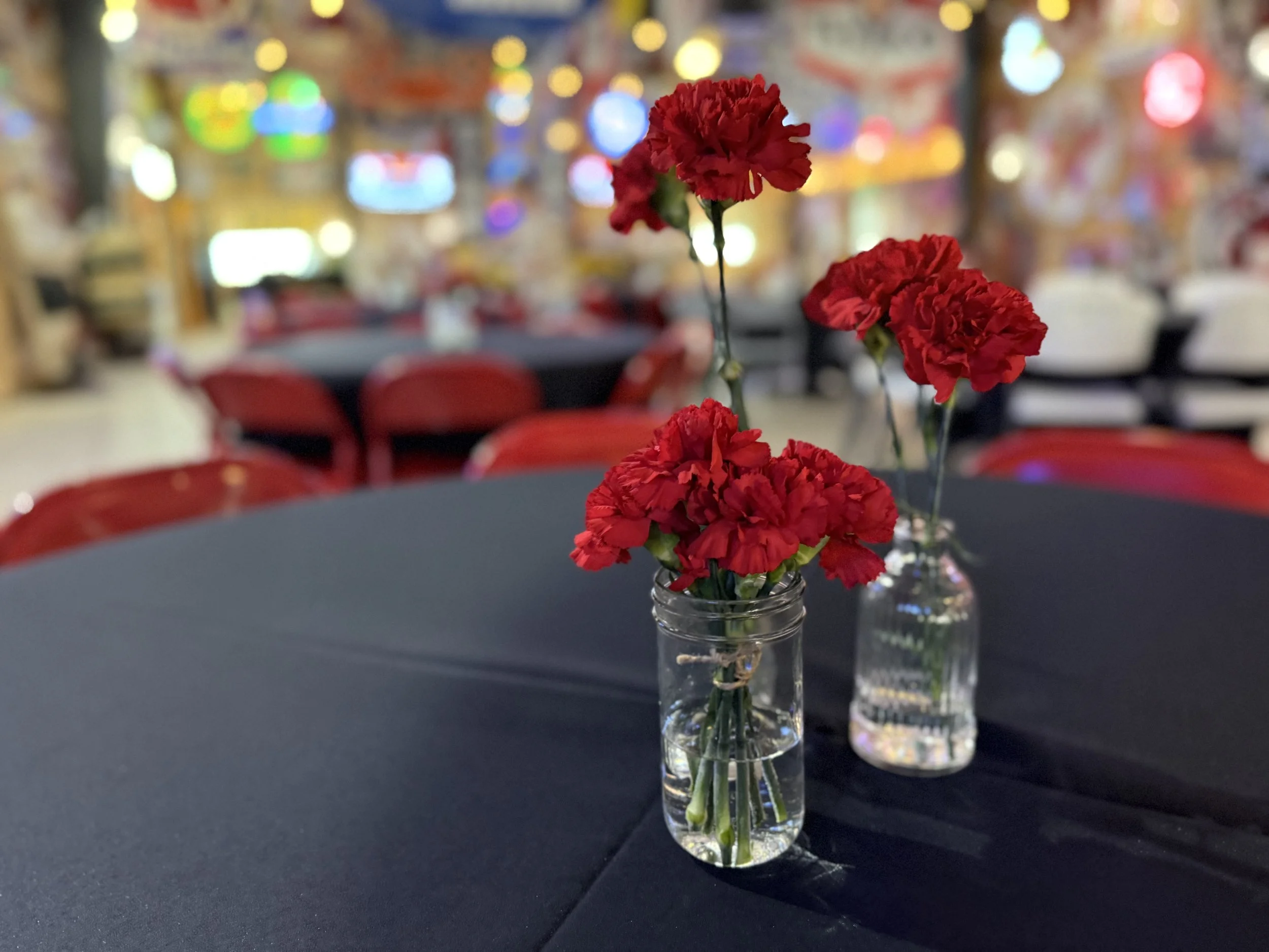 Charming red carnation centerpiece in mason jars, adding a pop of vintage romance to a table at Sparks Museum and Event Center—proof that even a few blooms can light up the room.