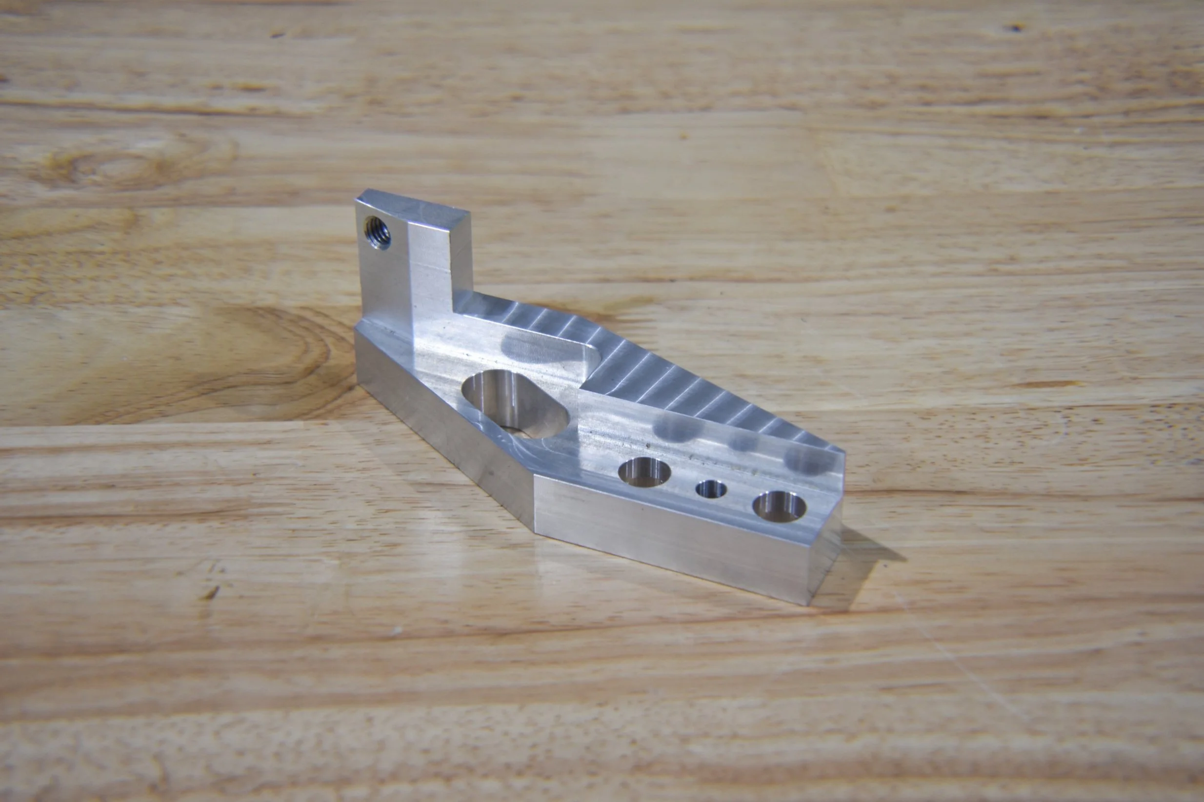 A nickel machined metal part with angled features.
