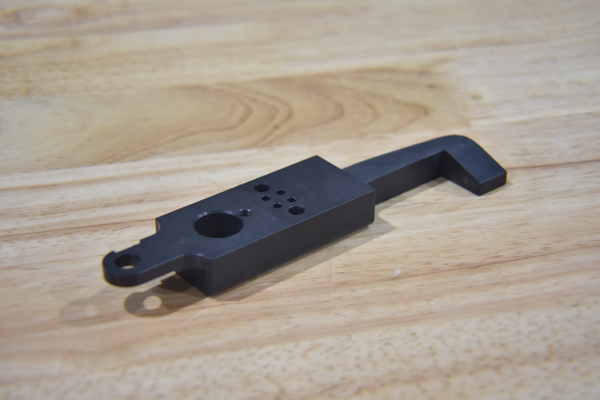 Black metal part with a bent arm.