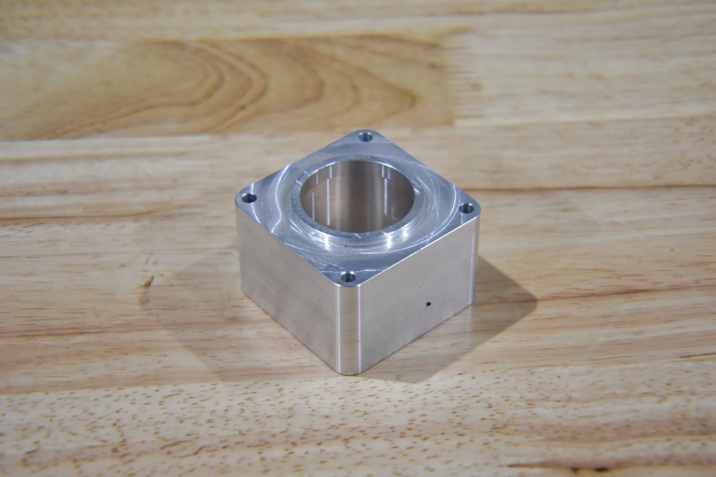A small metal cube with a circular hole in the center.