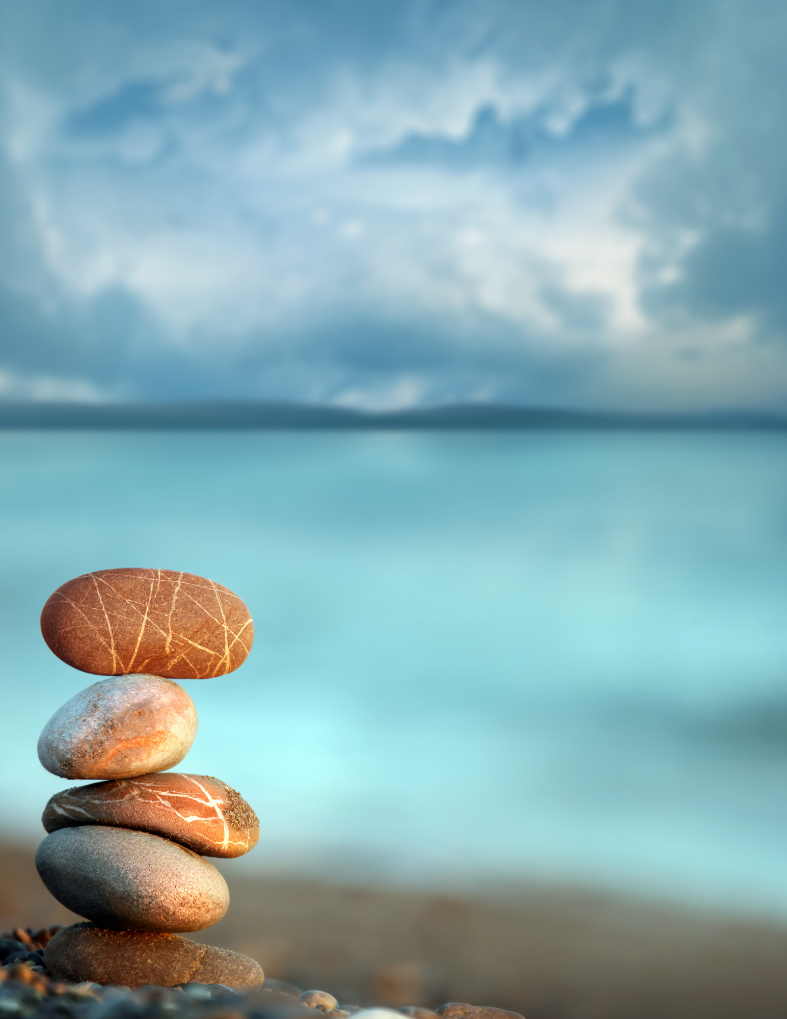 Stacked pebbles by the sea under a cloudy sky