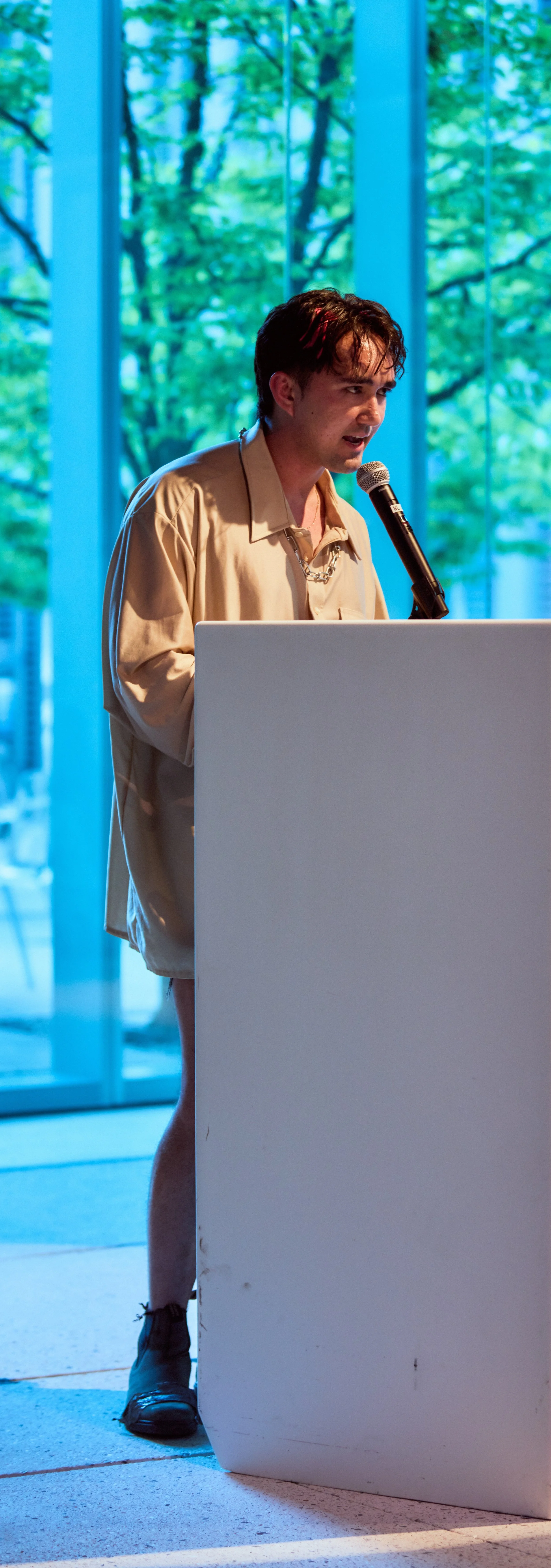 Rob reading at a podium in a chic beige shirt