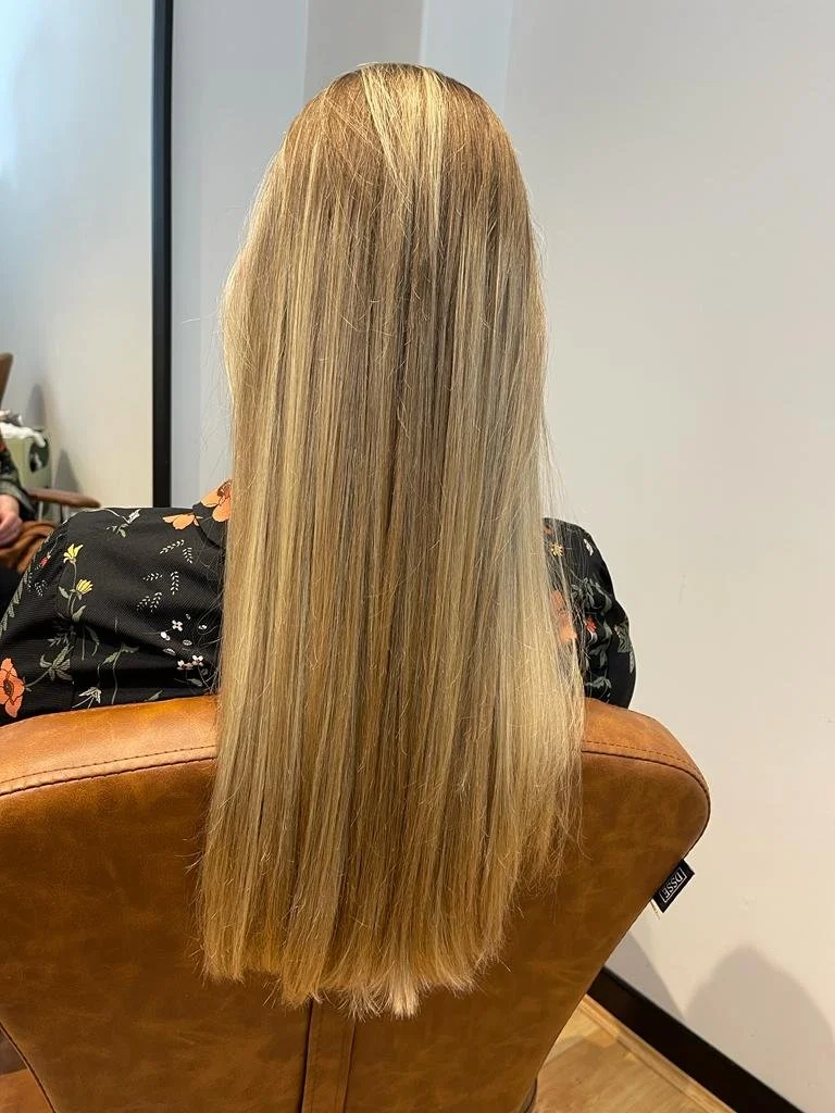 Person with long blonde hair sitting in a salon chair.