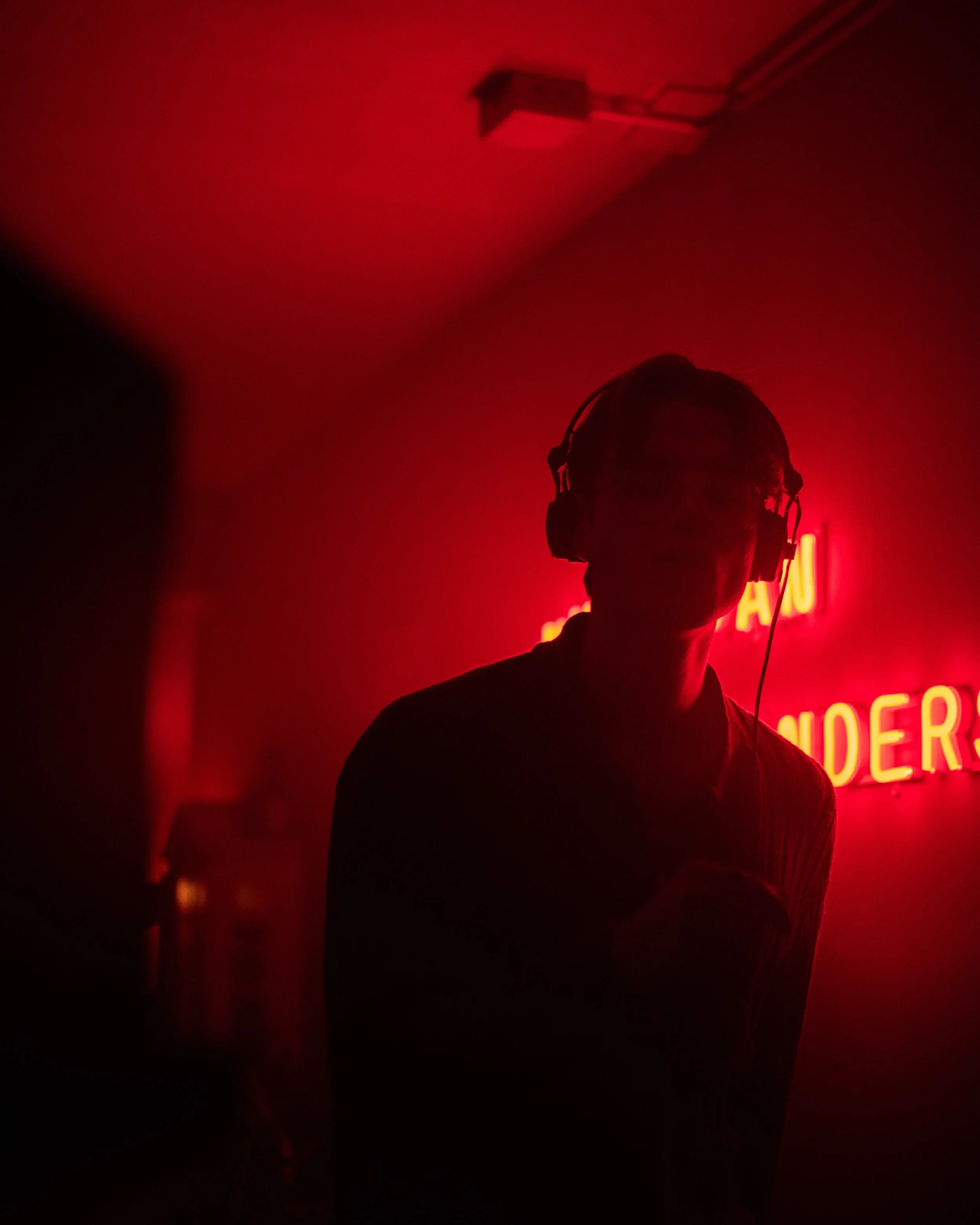 Silhouette of a person wearing headphones against a red neon-lit background.