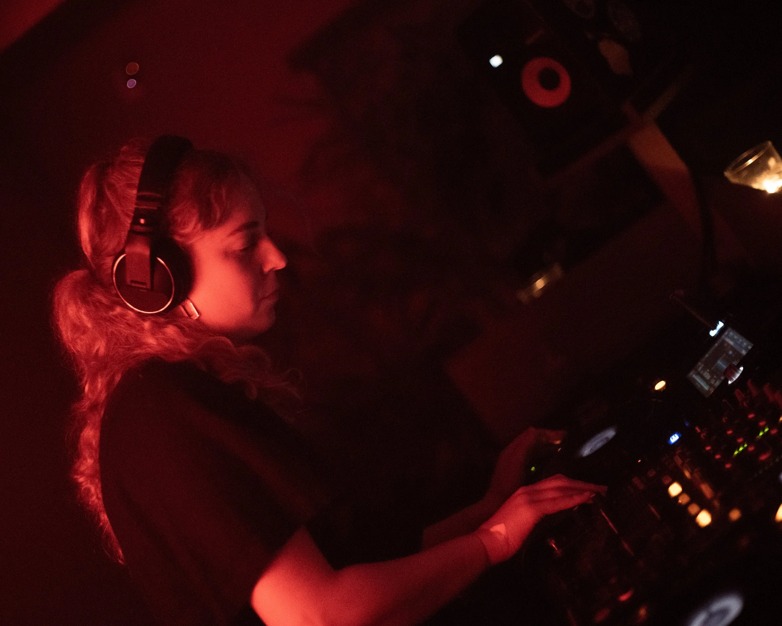 DJ performing with headphones and mixing console in dim lighting