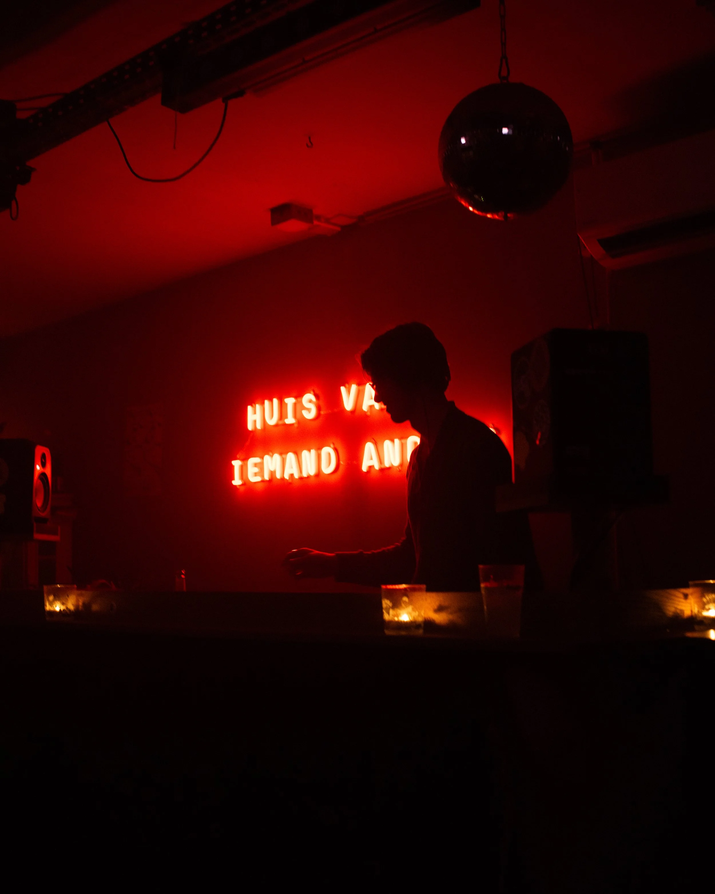 Silhouette in dimly lit bar with red neon sign and disco ball