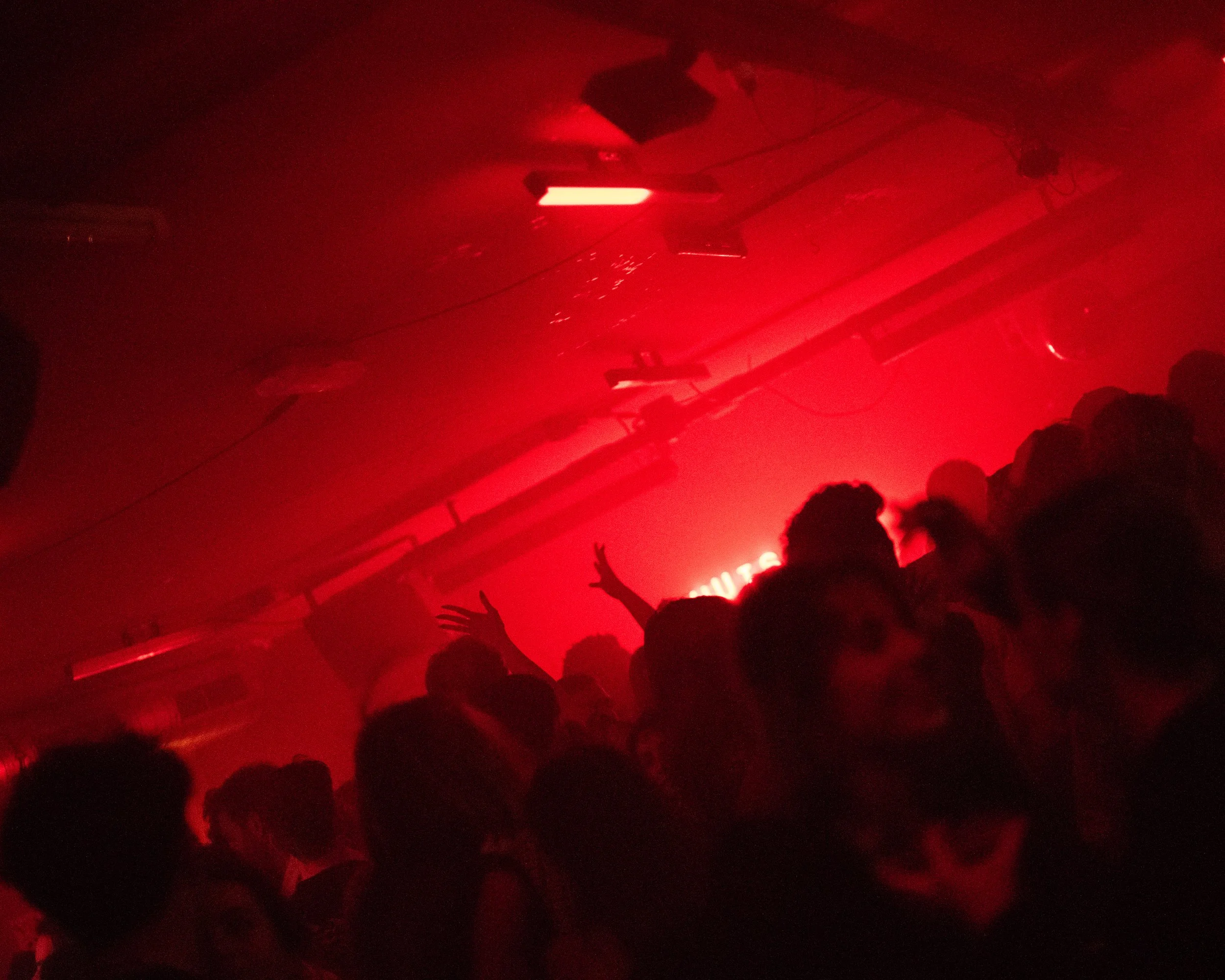 Crowded nightclub with red lighting and people dancing