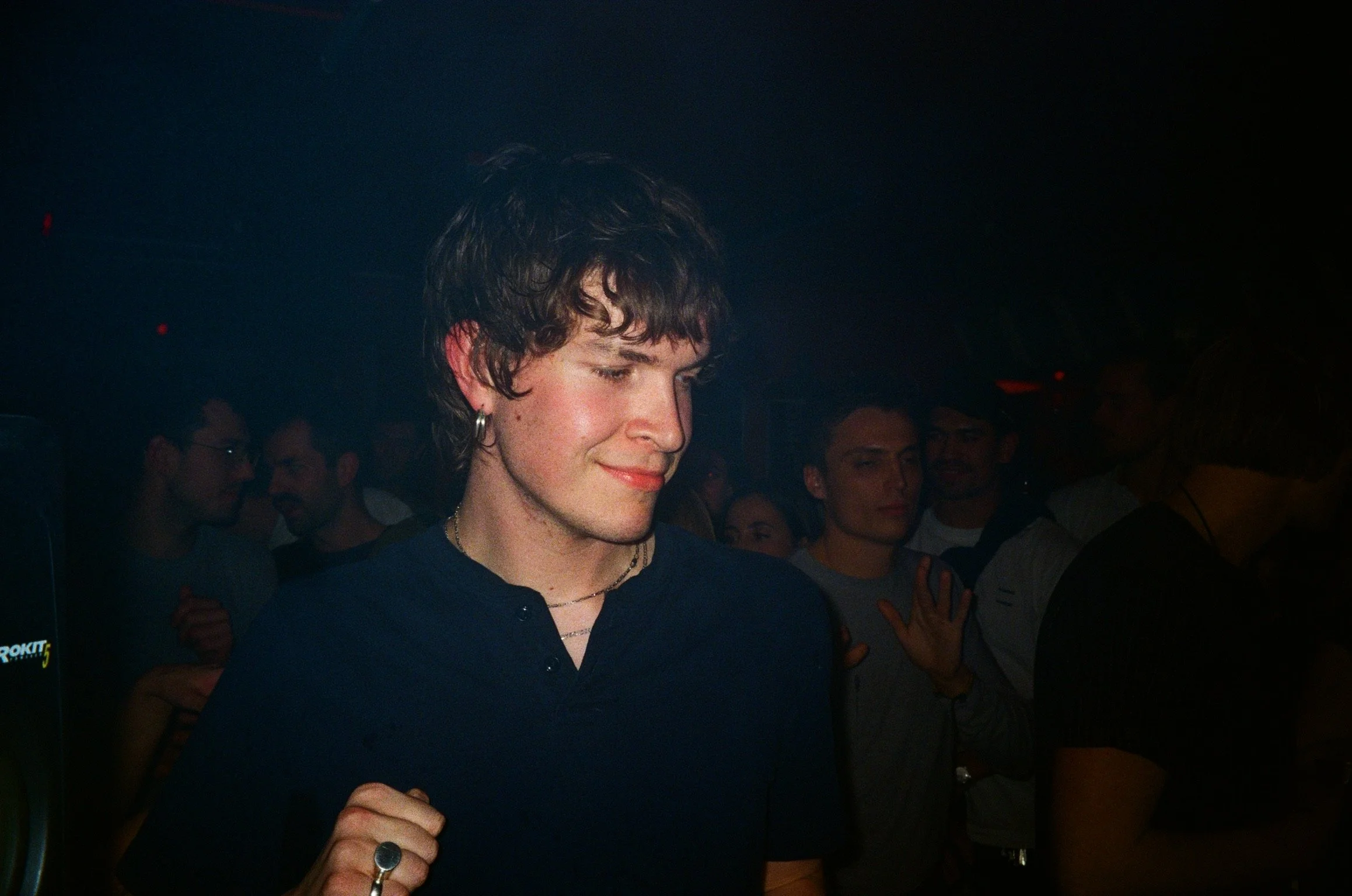 Person with curly hair and hoop earring at a crowded indoor event.