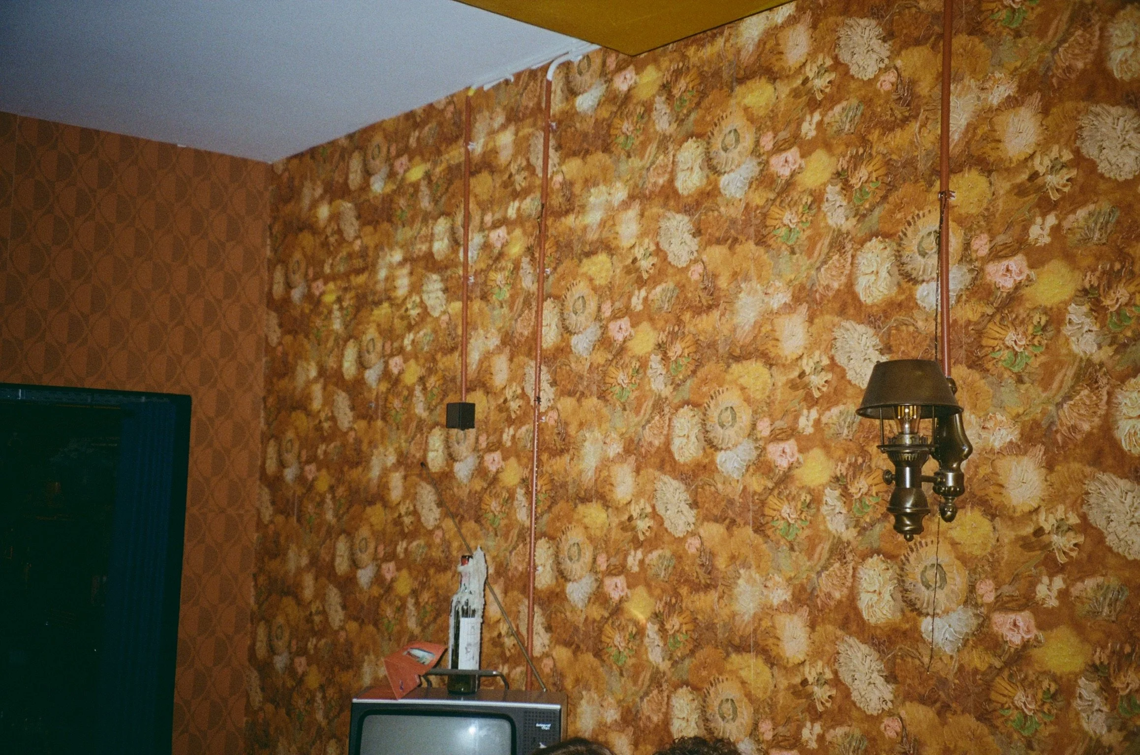 Vintage room with floral wallpaper, old television, and hanging lamp
