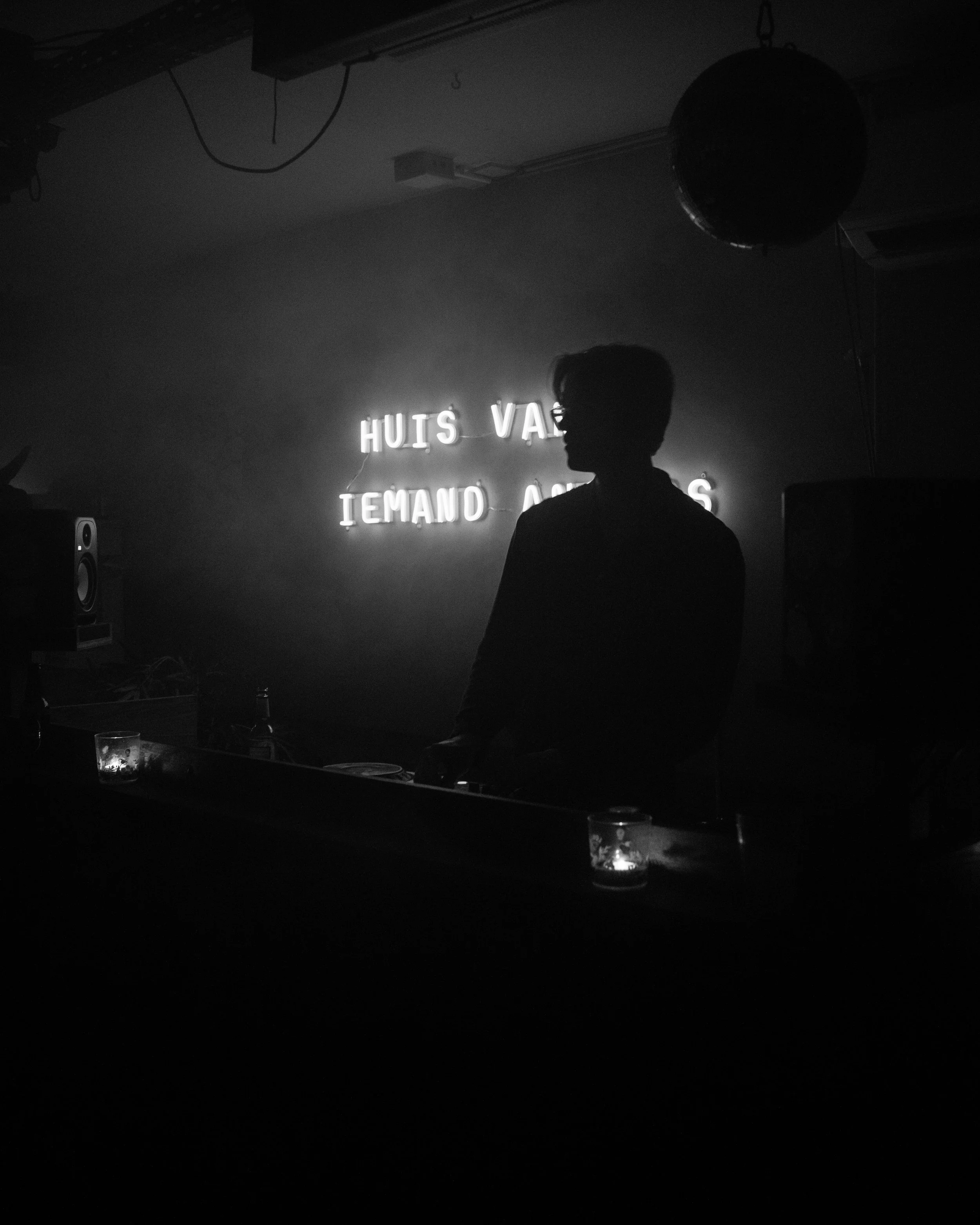 Silhouette of a person in front of neon sign in a dimly lit room.