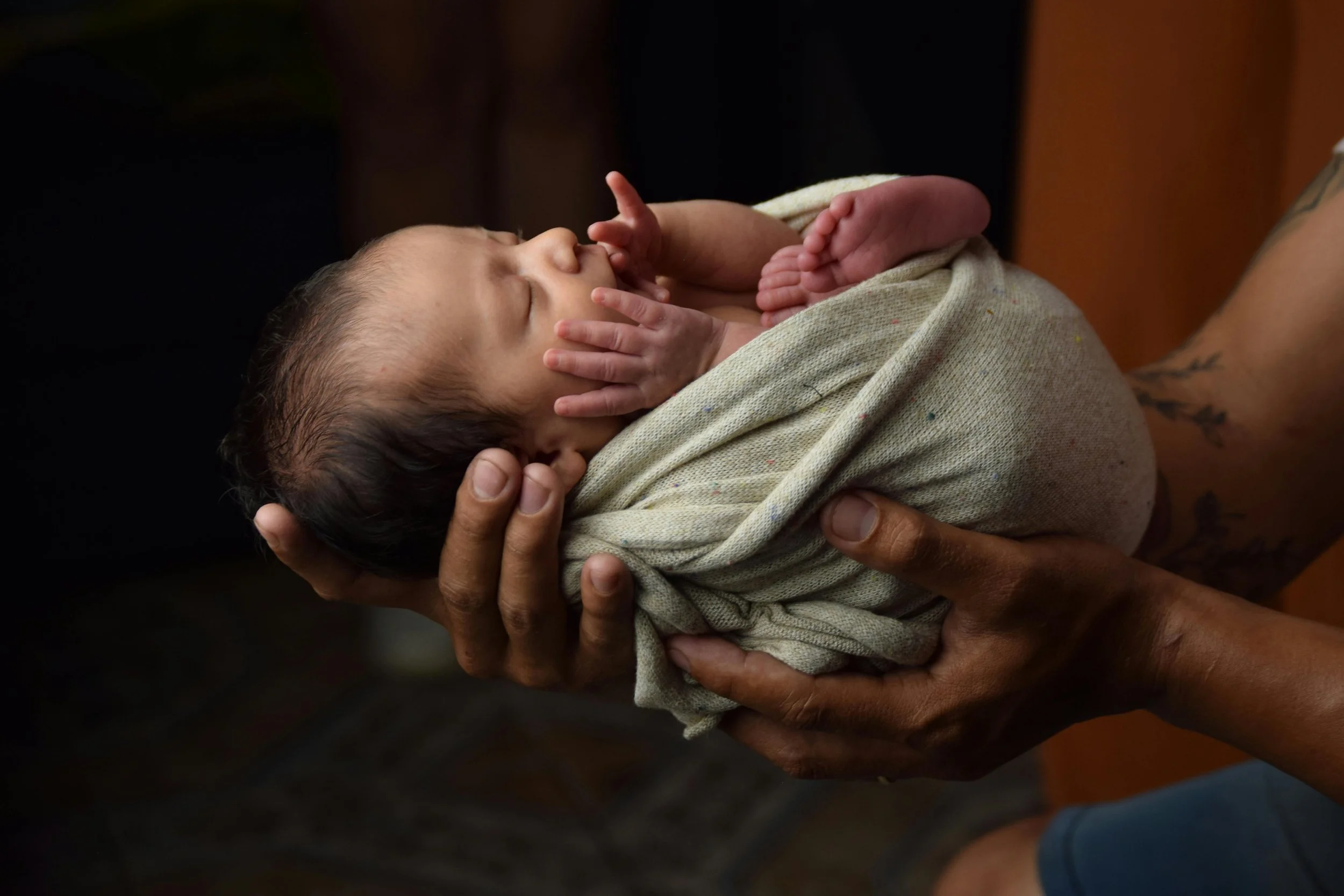 Close-up of a newborn baby's tiny feet with peeling skin, wrapped in a towel, lying on a blanket after a home birth.