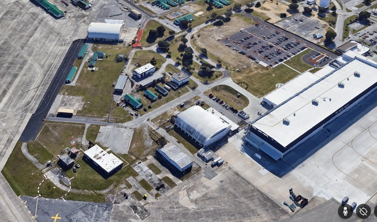 An aerial view of our hangar campus with multiple smaller buildings, parking lots, and surrounding roads.