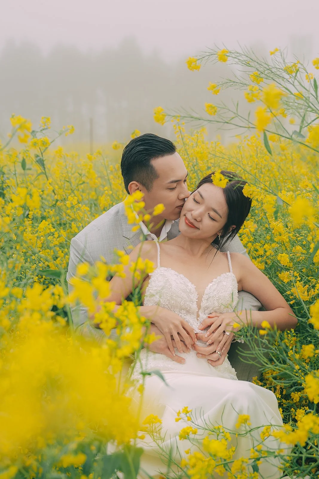 Panoramic lifestyle photography of yellow canola fields under a foggy grey sky near Jorangmal Jeju Island with a small figure in the scene
