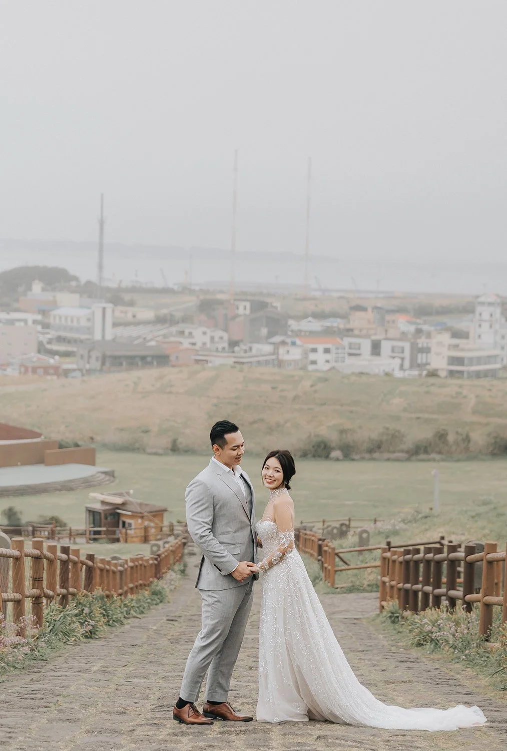 Wide-angle landscape photograph of Seongsan Ilchulbong headland with a small figure in the foreground on a foggy day in Jeju