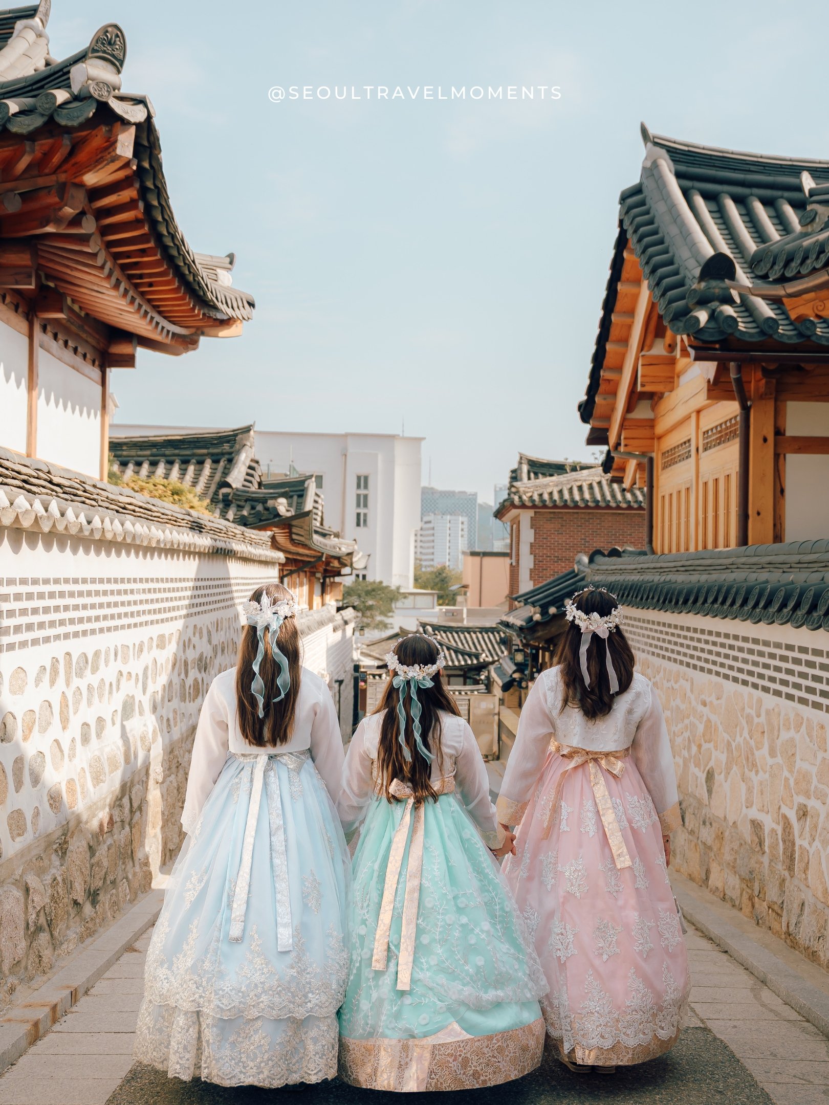 Candid moment of a mom and her daughters in traditional hanbok in a quiet Bukchon street