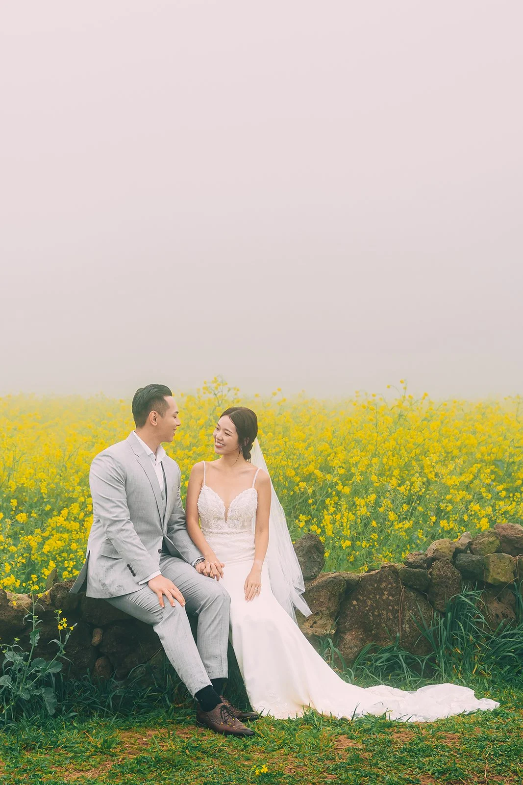 Couple portrait in bright yellow canola fields near Jorangmal on a foggy spring day, Jeju Island lifestyle photography
