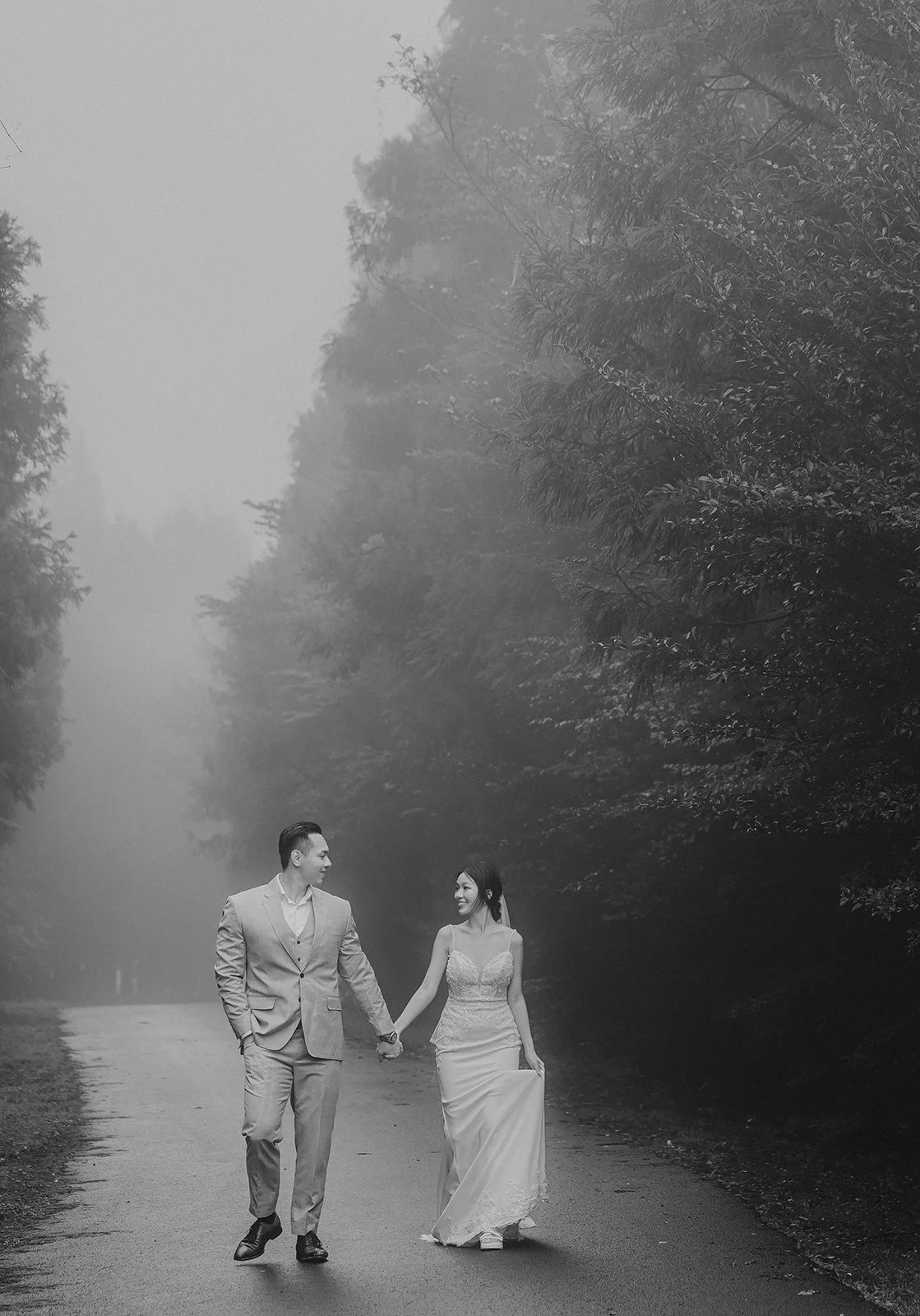 Cinematic portrait of a person standing in the symmetrical tree alley near Blaize Resort entrance on a foggy morning in Jeju Island