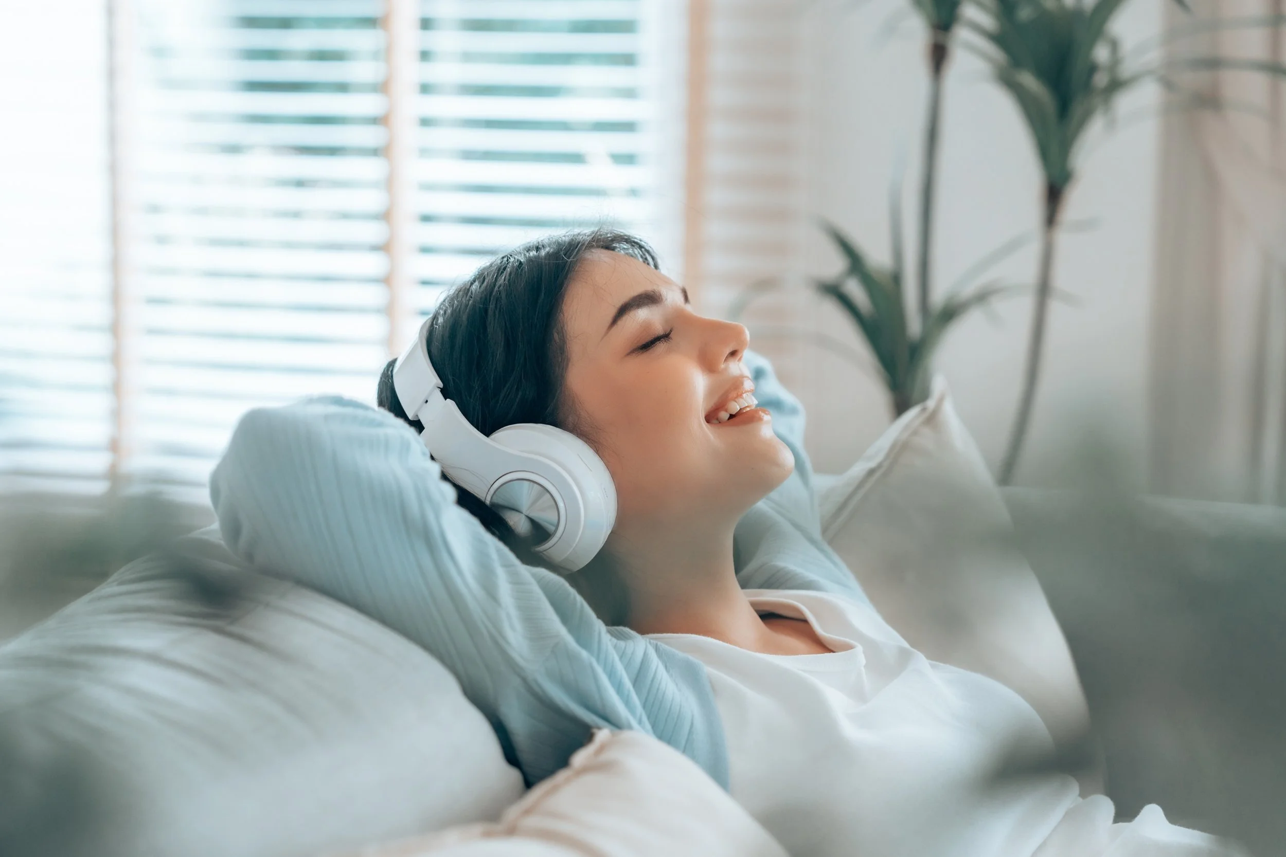 Fau liegt auf dem Sofa mit Kopfhörern und lächelt.