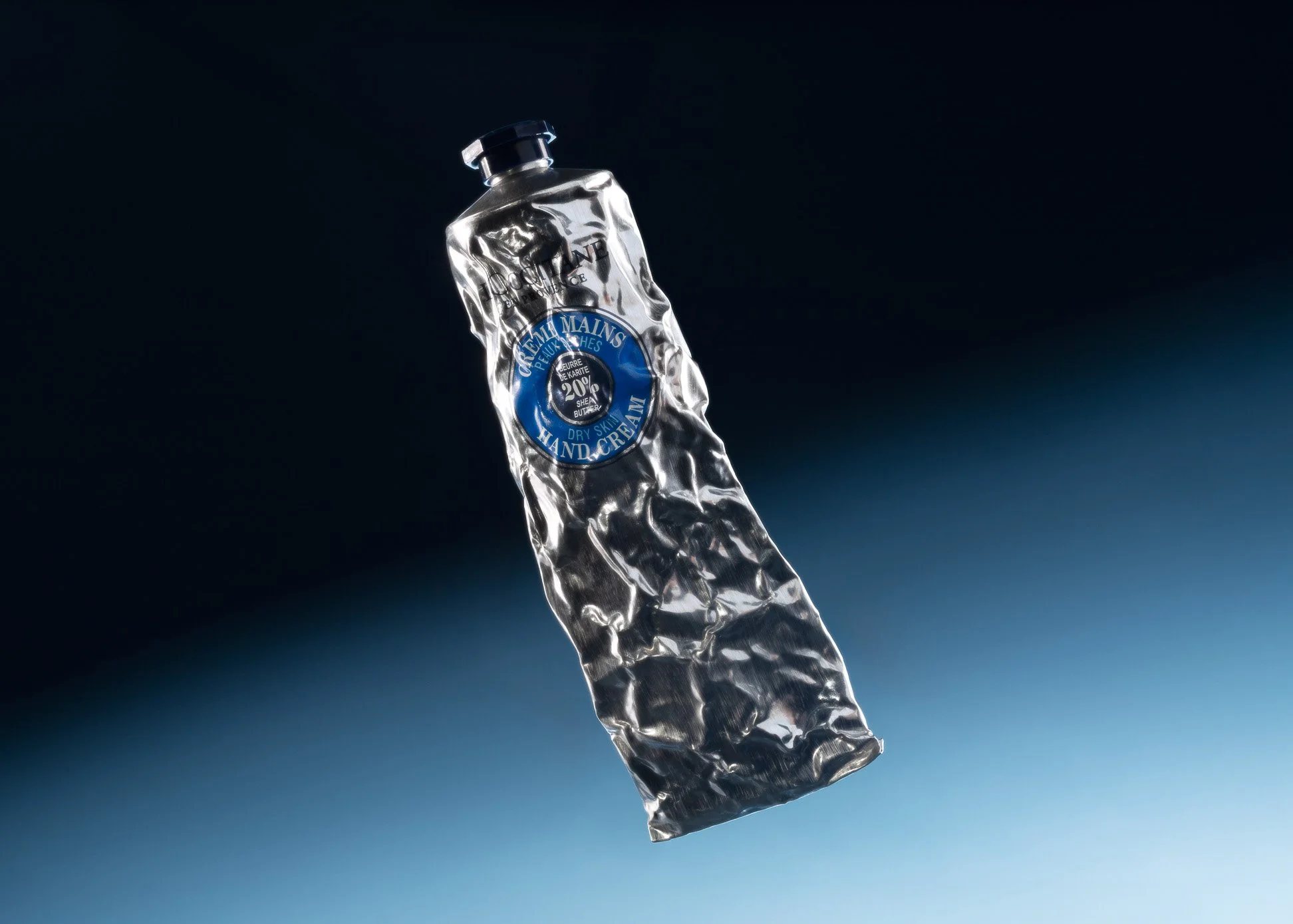 A crumpled tube of hand cream with a blue and white label floating against a dark background.