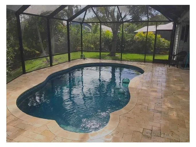 Freeform pool with travertine stone pavers and screen enclosure.jpg