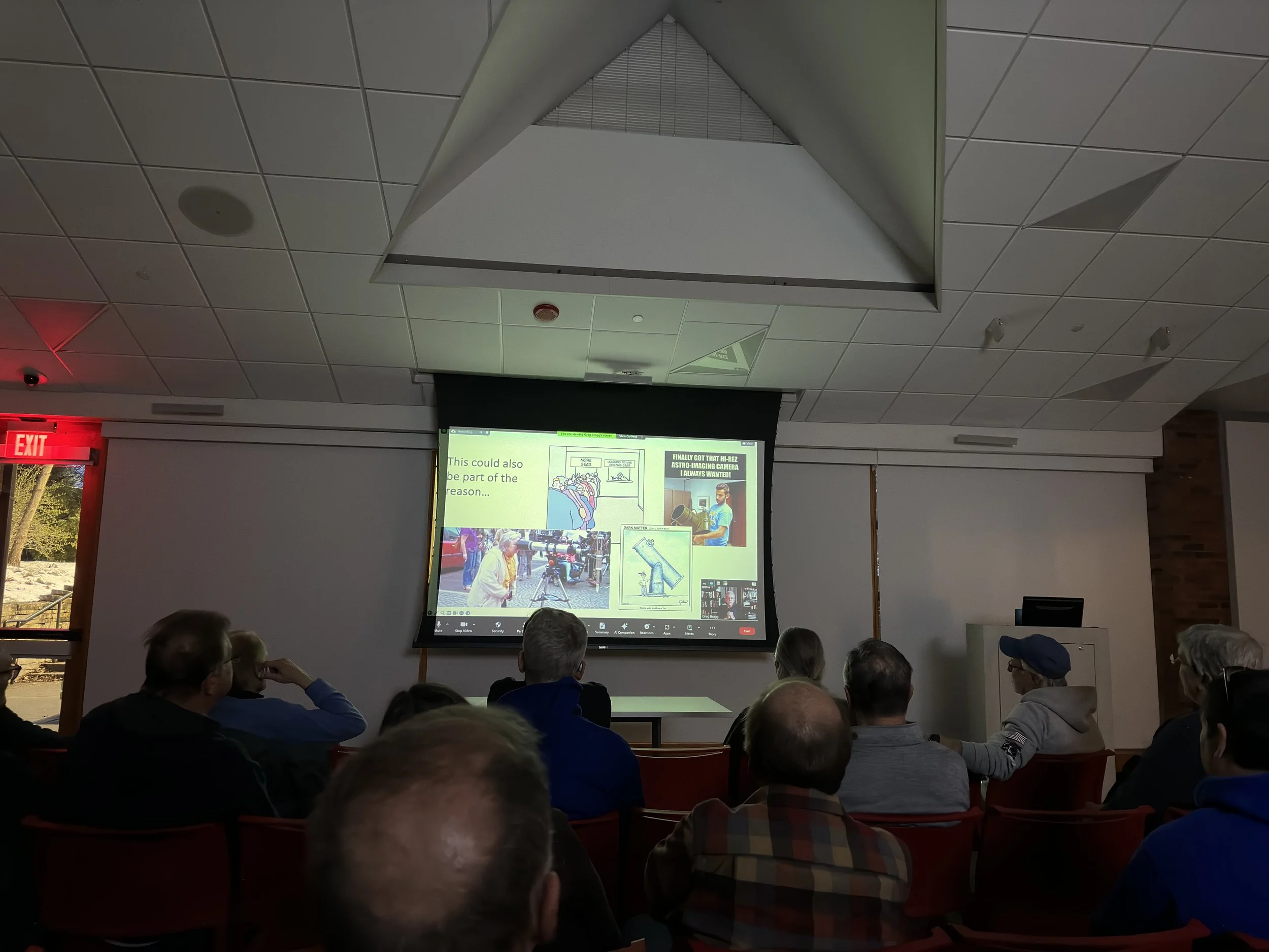 Audience watching a presentation on a projector screen in a conference room.