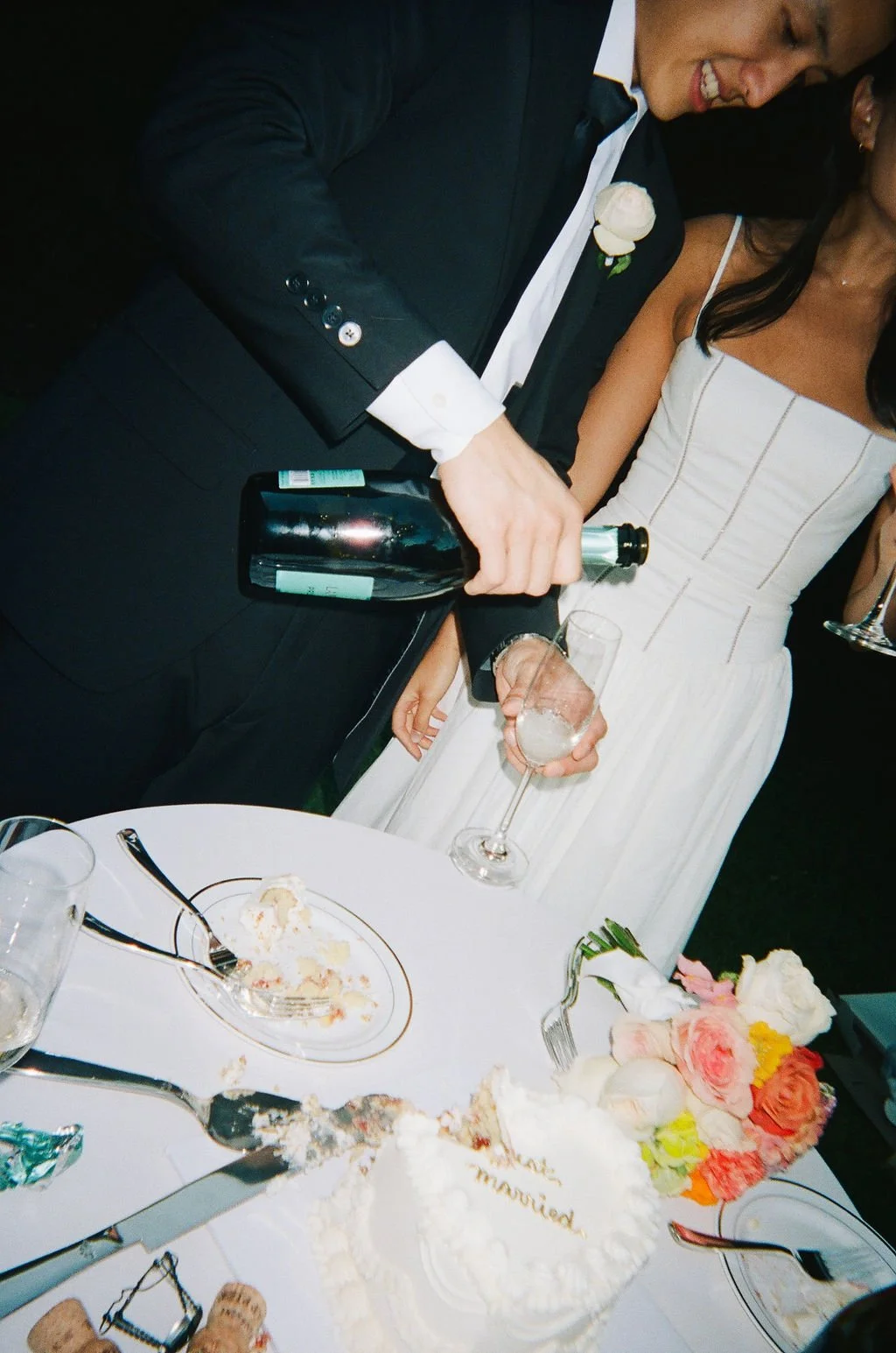 couple pouring champagne with just married cake