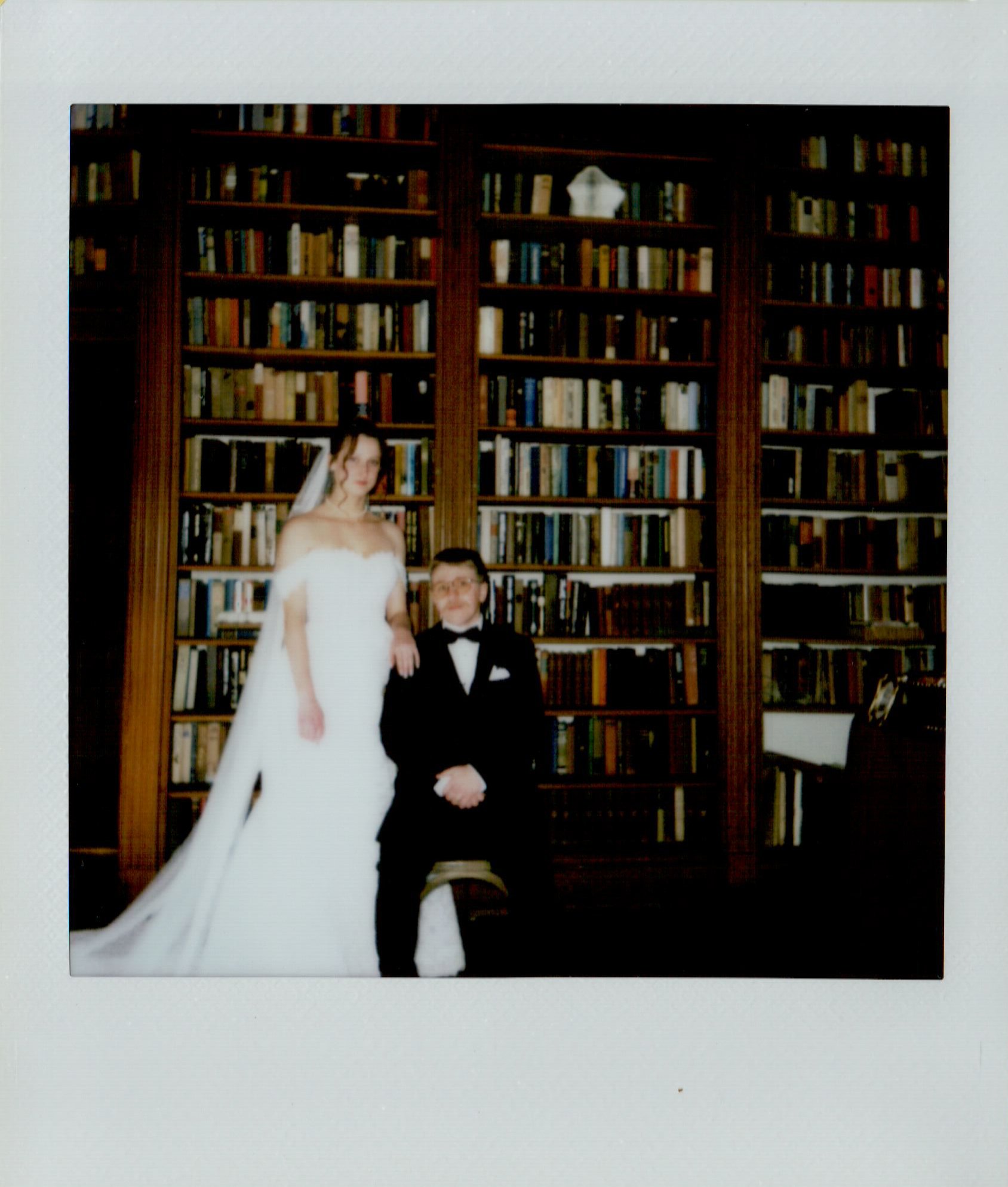 bride and groom in front of bookcase