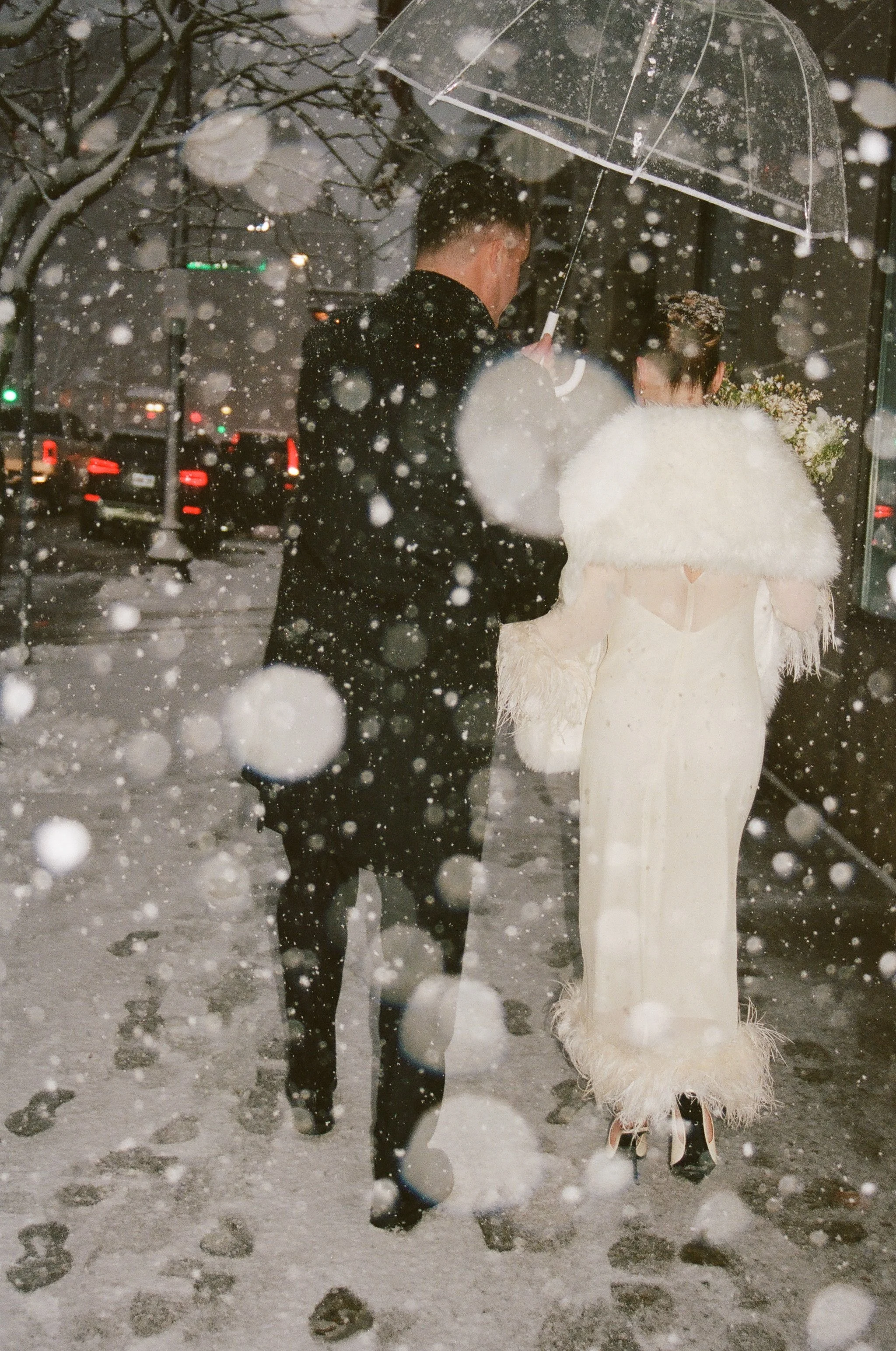 Boston couple walking in snow under clear umbrella