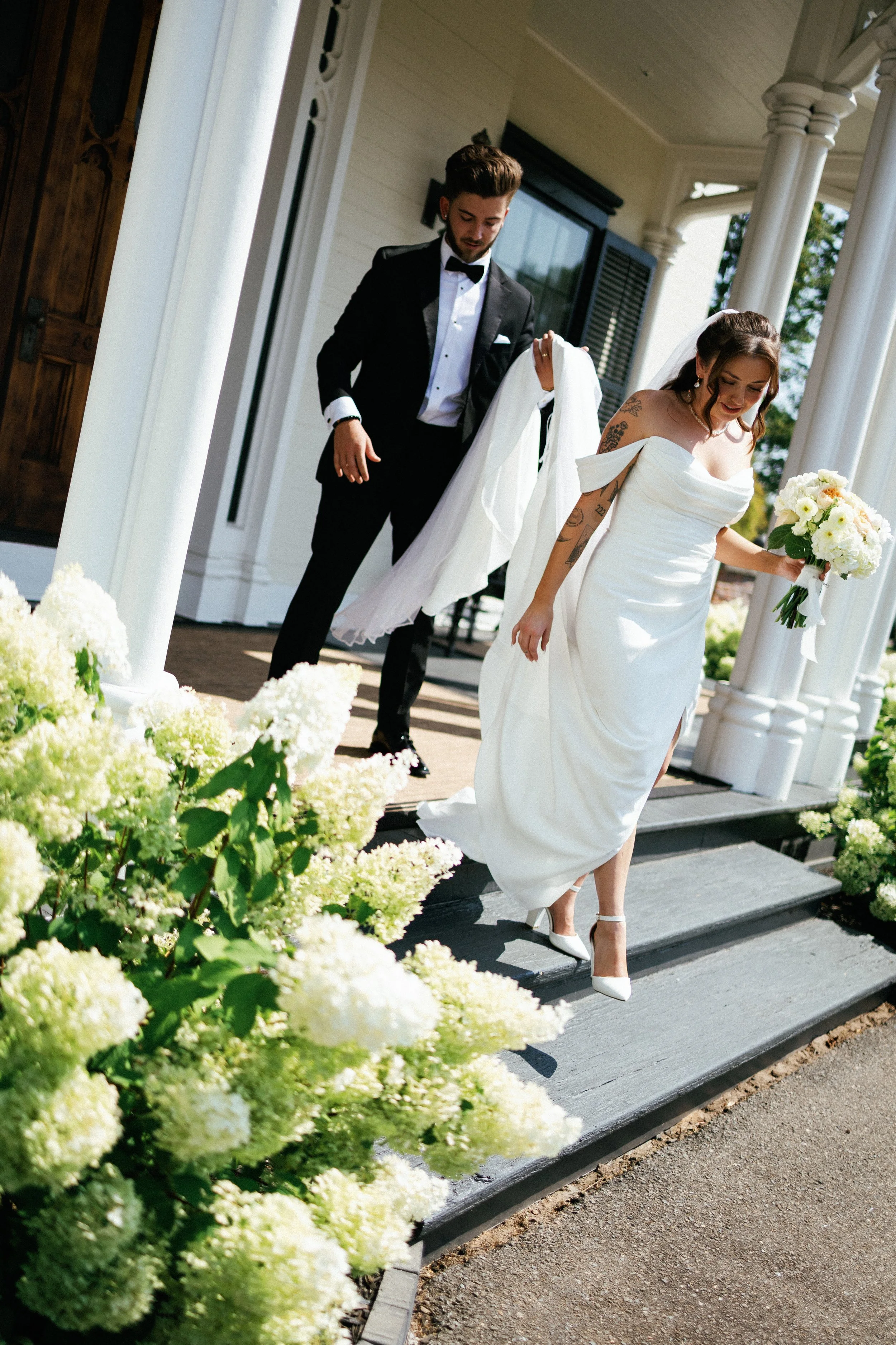 bride in wedding gown holding bouquet walking down stairs with border