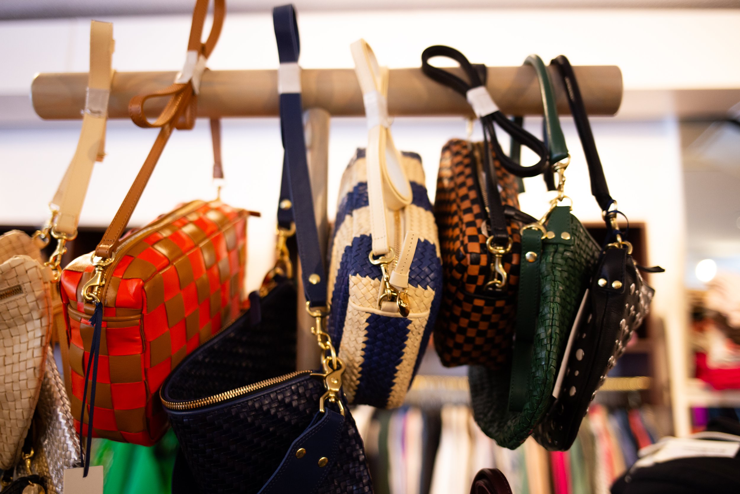 Various sized hanging purses in different woven styles and lengths.