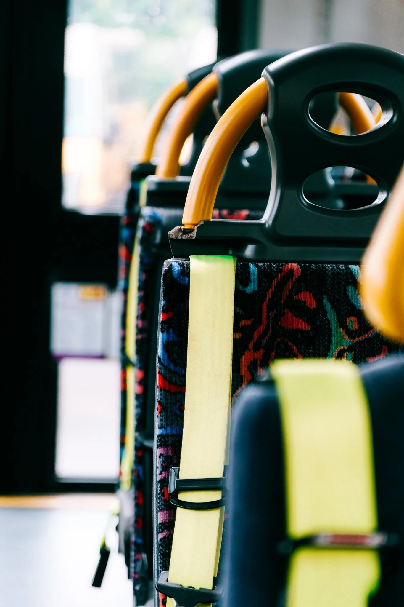 Bus seats with yellow handrails and patterned fabric upholstery.