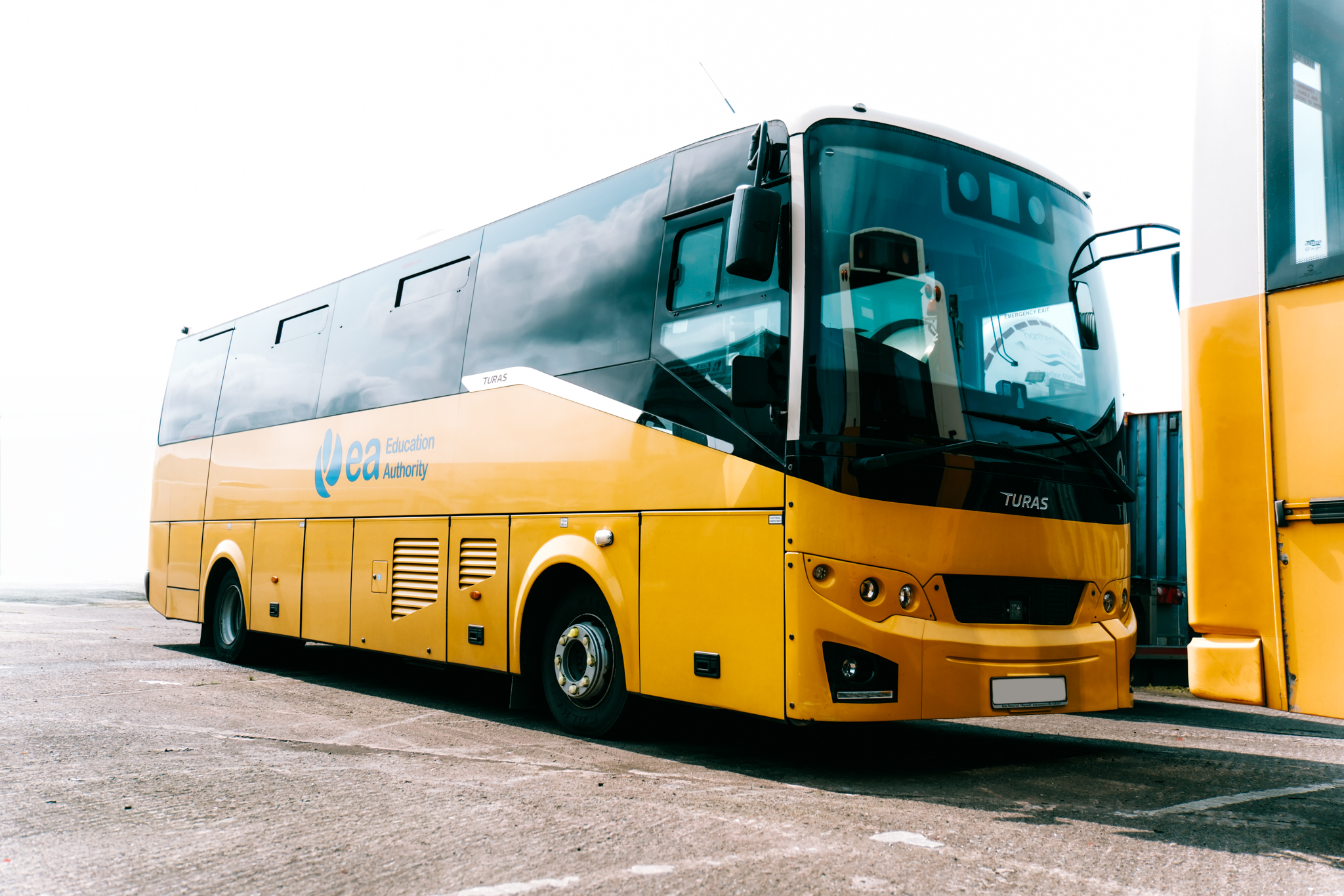 Yellow bus with 'EA Education Authority' logo parked at a bus station.
