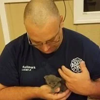 Captain KB Hallmark IV holding a kitten that was rescued from underneath the water tank from Brush 5723.