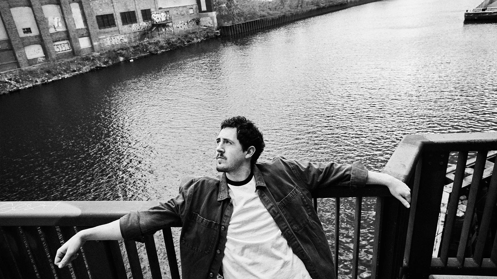 Michael Marcagi leaning on a ledge above a river, looking into the distance.