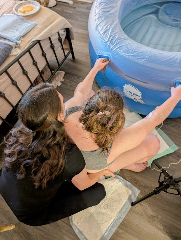A woman squats near a birthing tub as she labors at home with a doula to get her VBAC birth in san antonio
