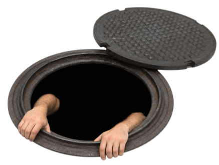 A person is looking out from a sewer or storm drain opening with their hands gripping the edge, and the cover is open and tilted to the side.