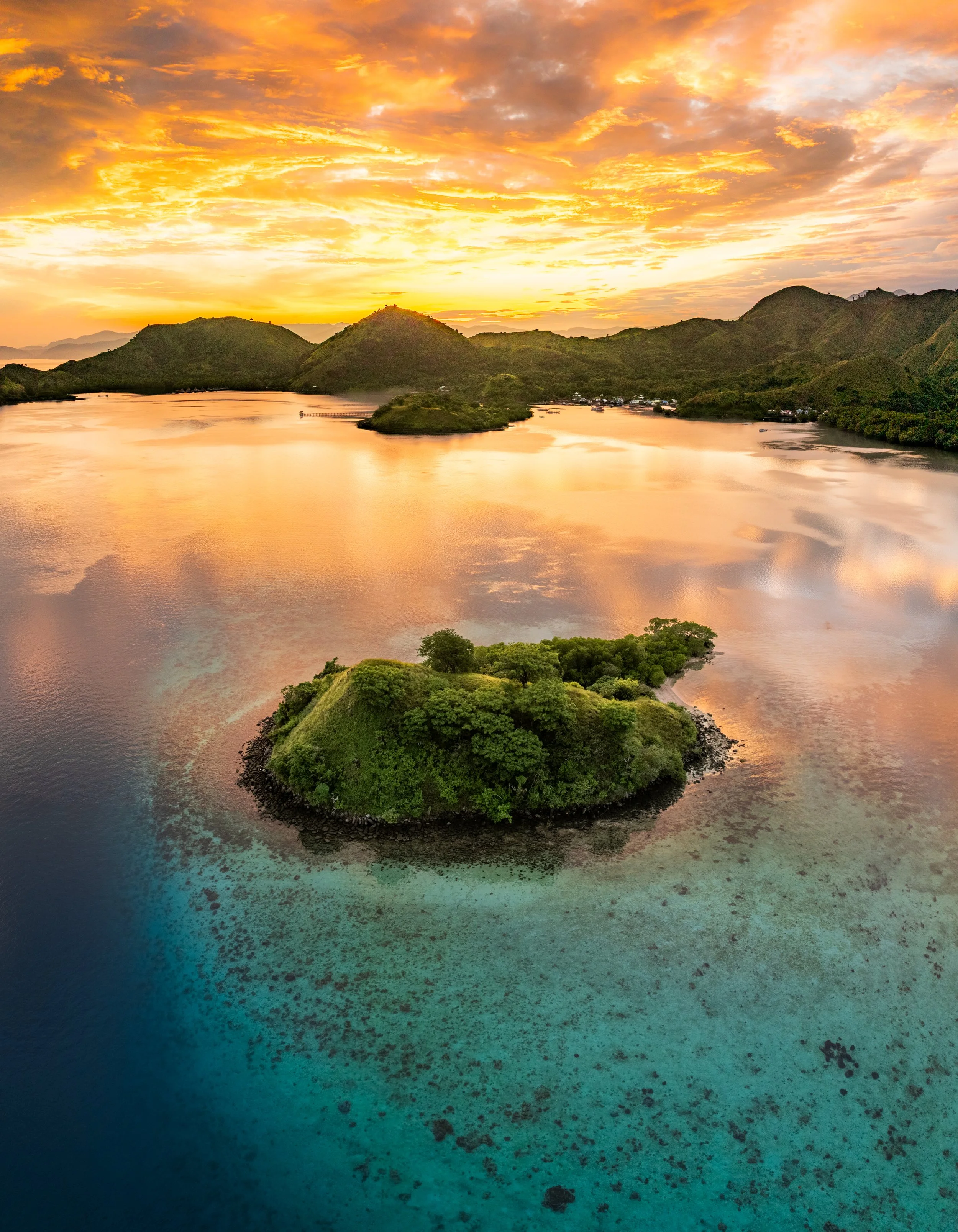Sailboat on calm water at sunset with a hillside in the background