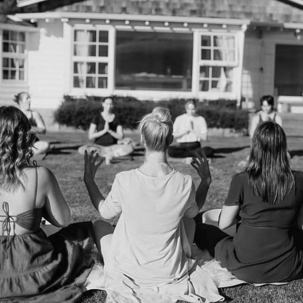 Group of women practicing yoga outdoors on a sunny day.