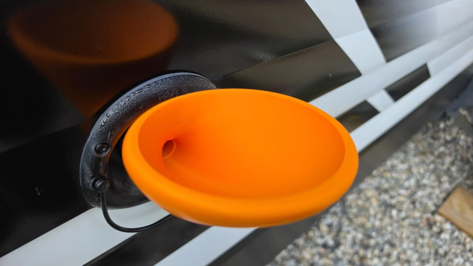 Pouring water into an RV gravity fill port using the FlowPort anti-spill camper funnel.
