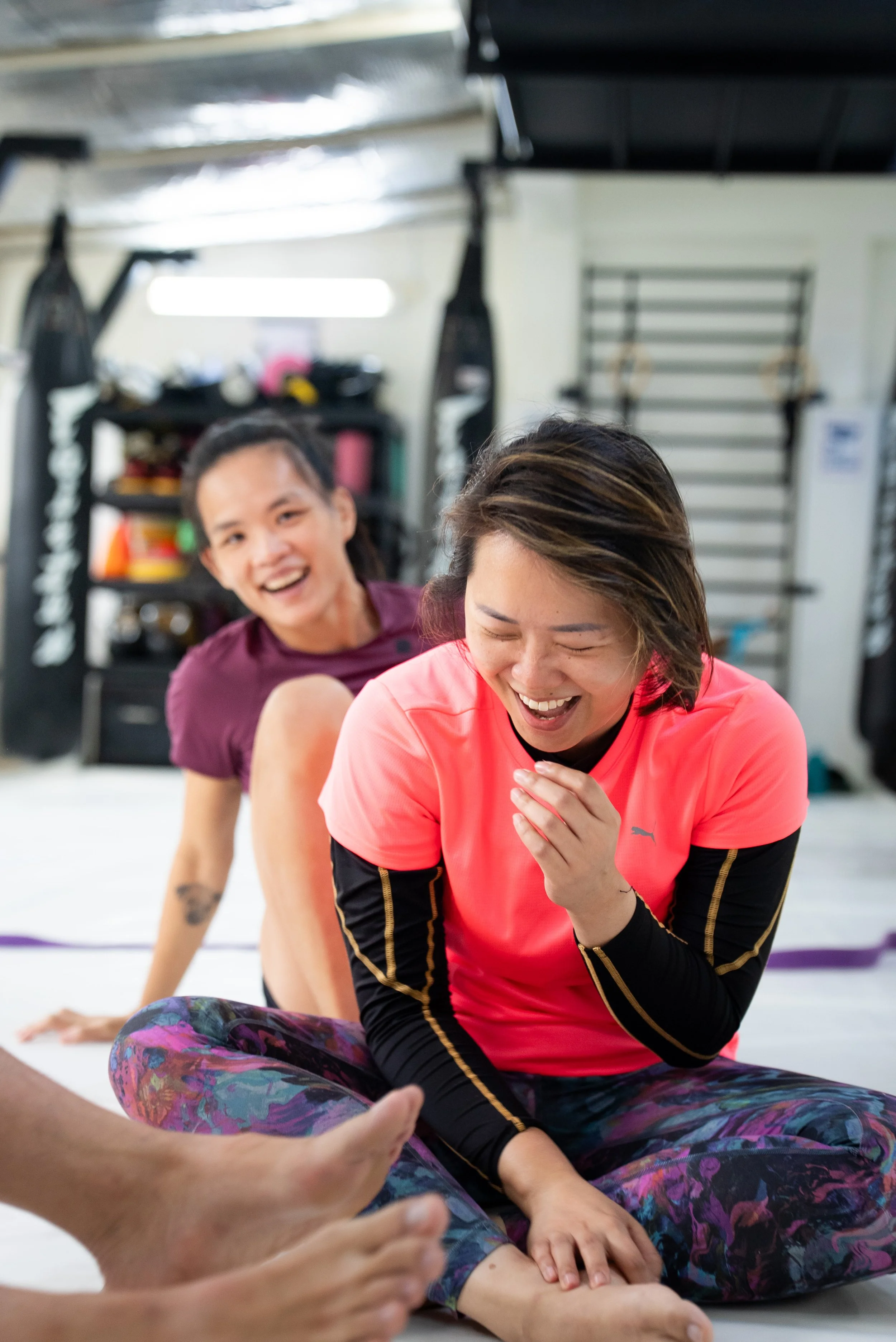 Female martial artists smiling during a no-gi grappling session, highlighting the supportive environment of the women's martial arts program