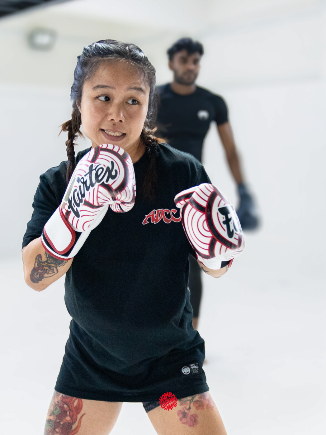Female coach teaching boxing drills to a student in a bright, modern martial arts gym