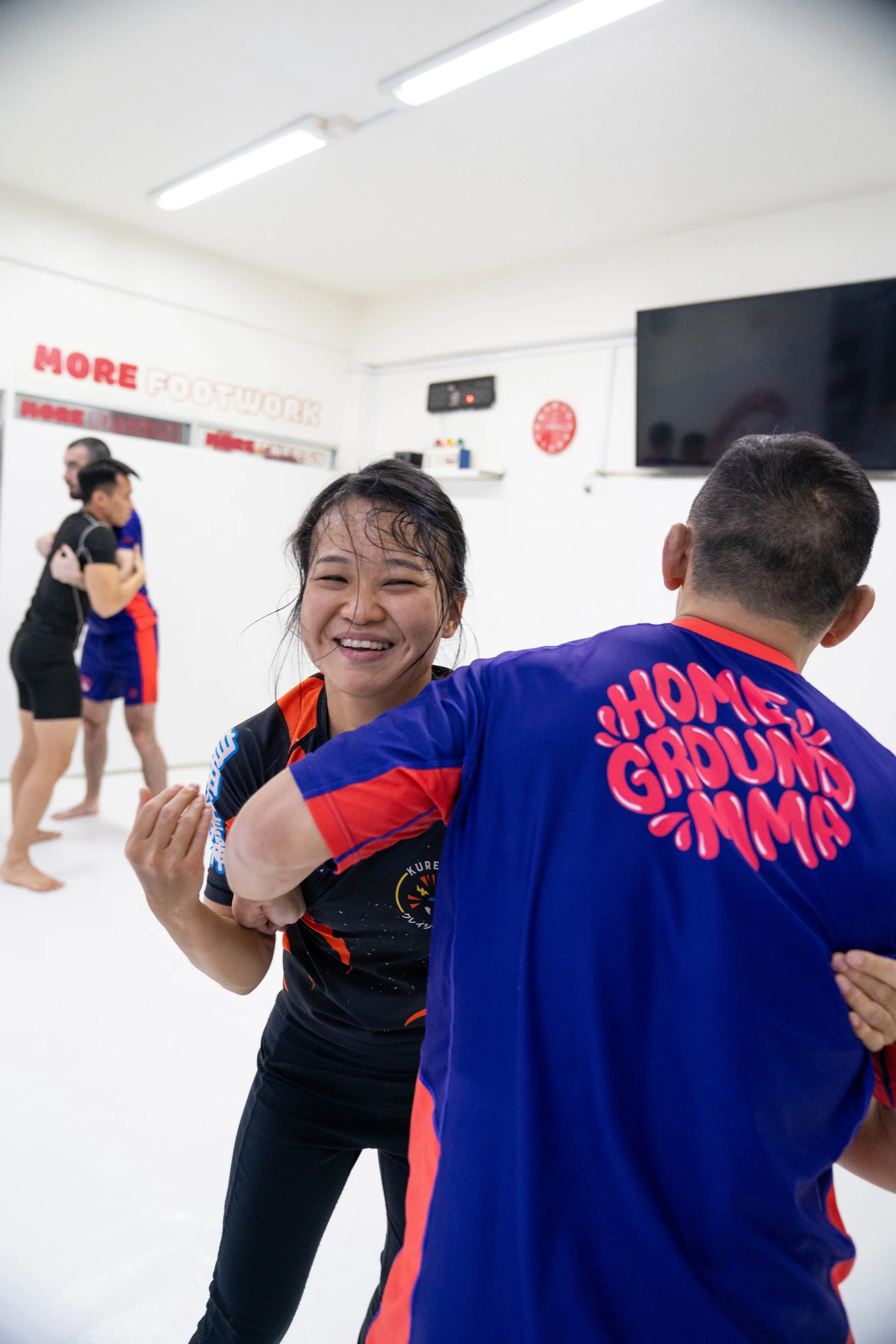 A female athlete practicing wrestling takedowns and clinch work on the mats during a technical martial arts training session.
