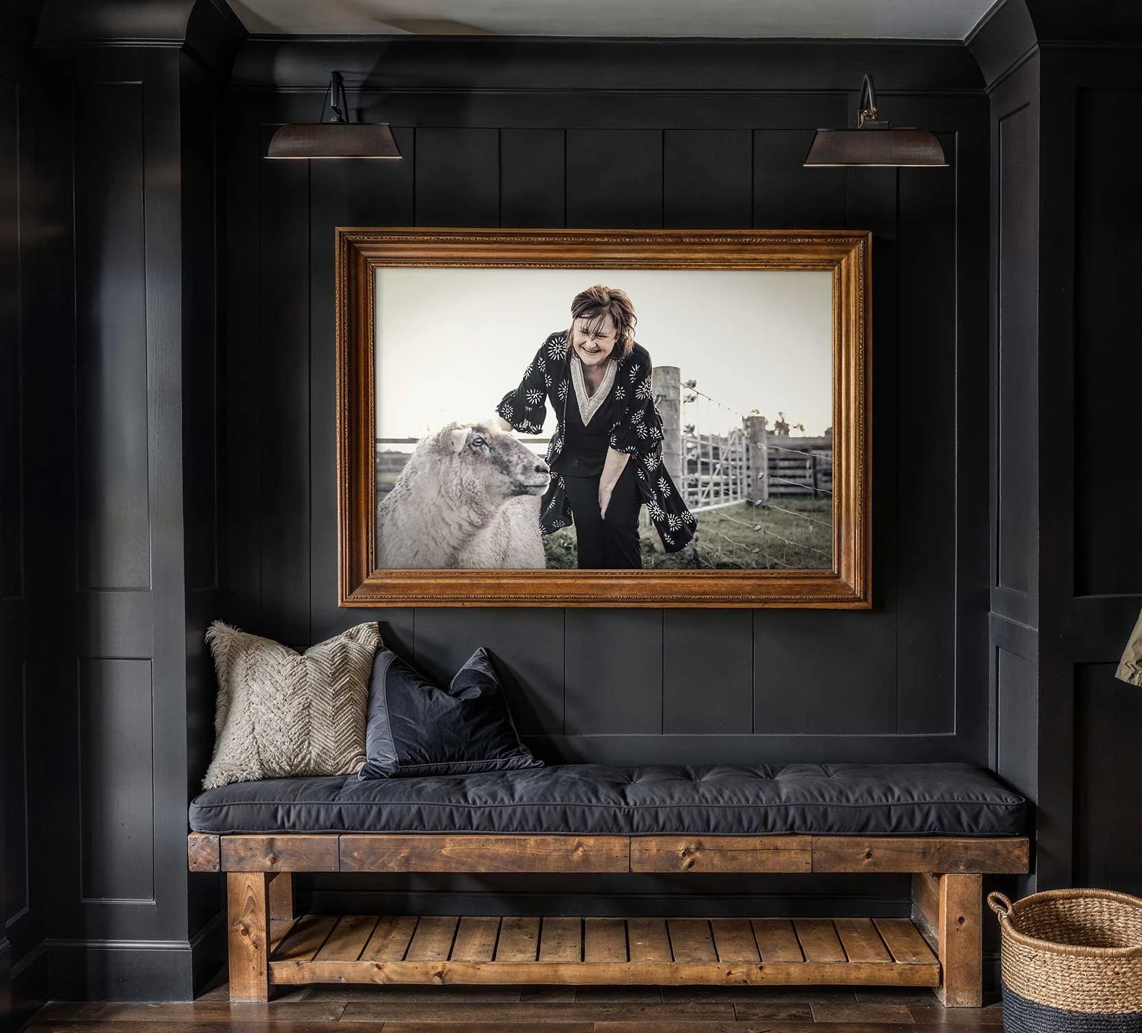 Large framed photo on a dark wall showing a woman smiling and leaning over a sheep in a farm setting.