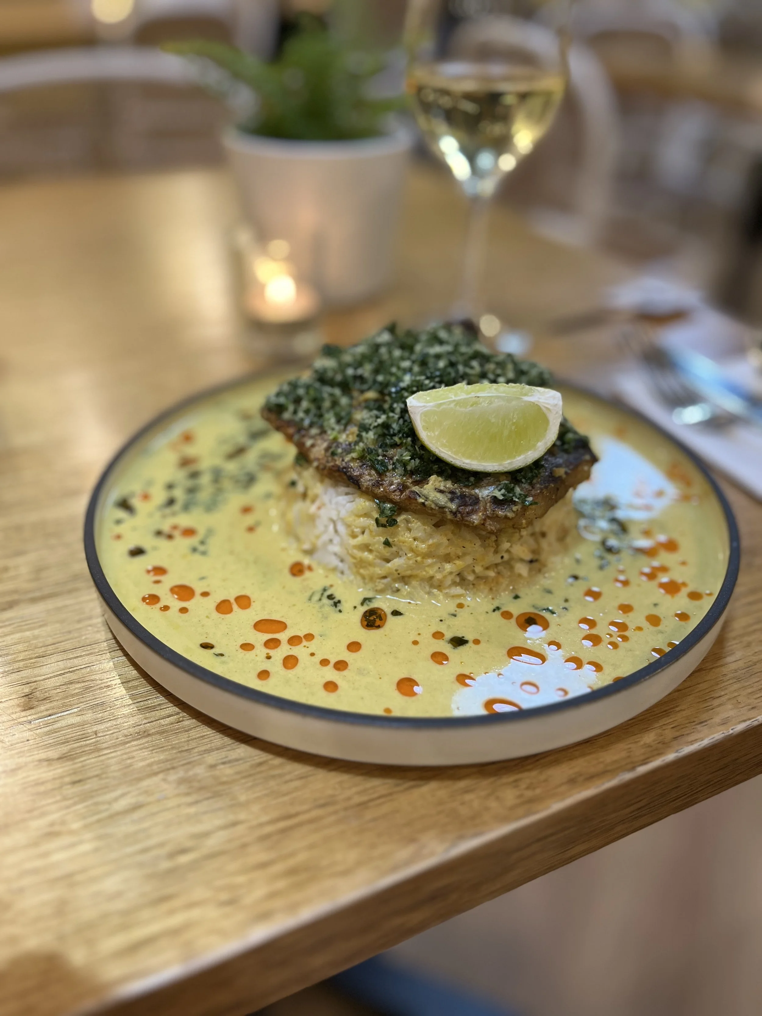 Our most popular dish - Barramundi Kiri Hodi Fillet of Barramundi settled on a creamy coconut gravy with chilli oil and coconut rice, topped with kale sambol and crisply shallots.