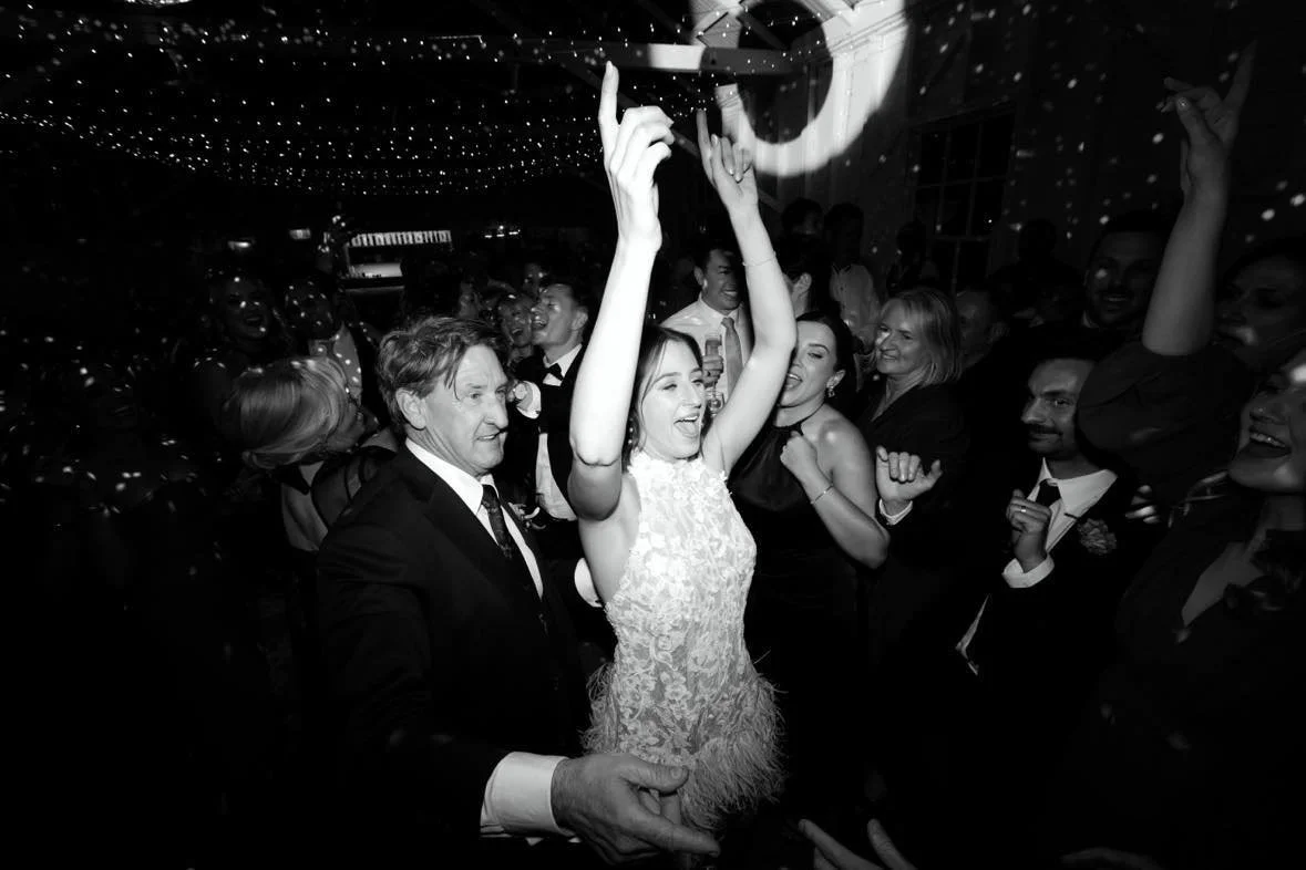 People dancing and celebrating at a party with disco lights and a festive atmosphere.