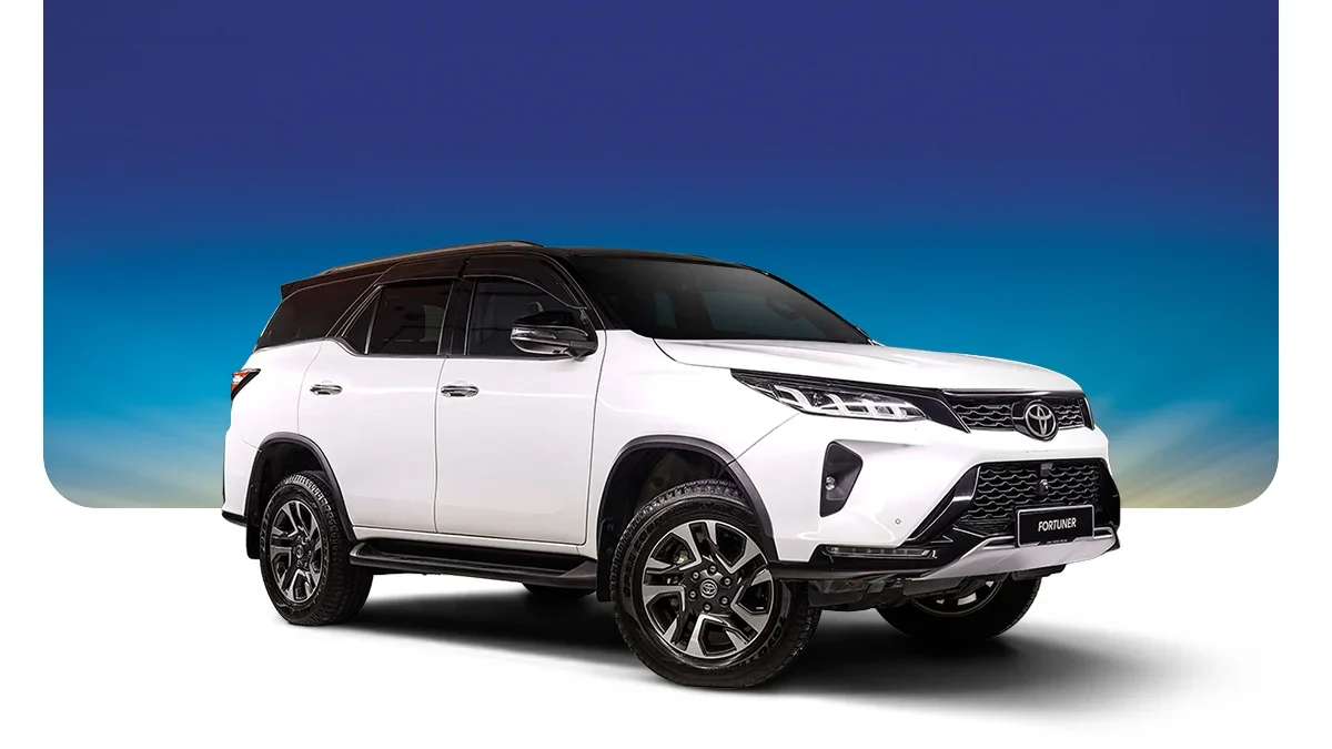White Toyota Fortuner SUV with black accents parked against a colorful gradient sky background.