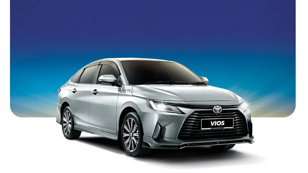 Silver Toyota Vios sedan in front of a colorful sky background.