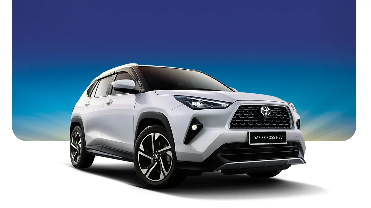 Silver Toyota Yaris Cross HEV compact SUV parked outdoors with a gradient blue sky background.