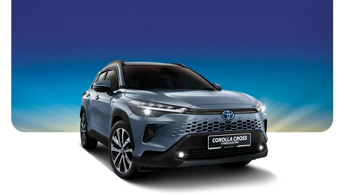 A blue Toyota Corolla Cross hybrid electric SUV on a white surface with a gradient blue sky background.